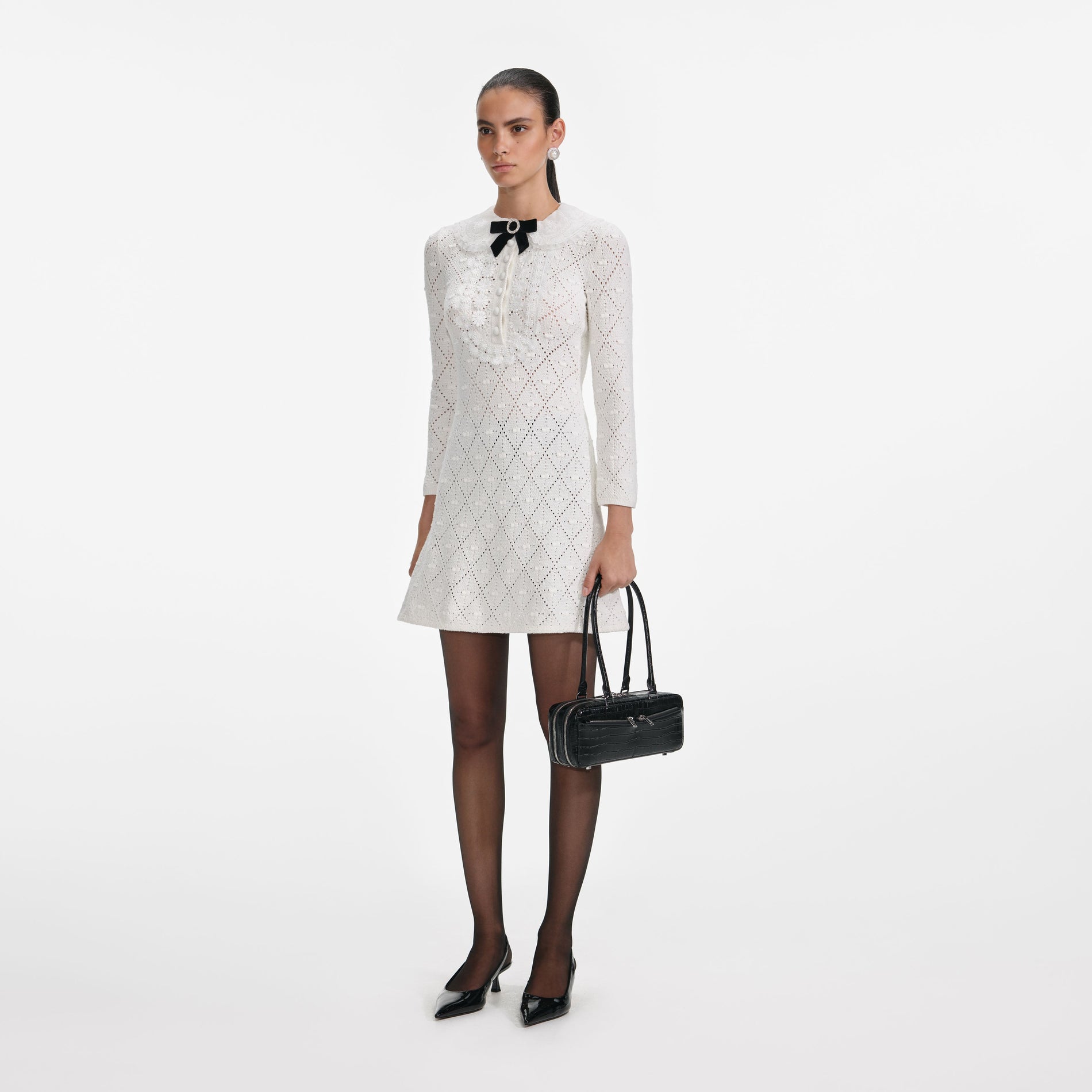 Side view of a woman wearing the White Lace Bib Knit Mini Dress