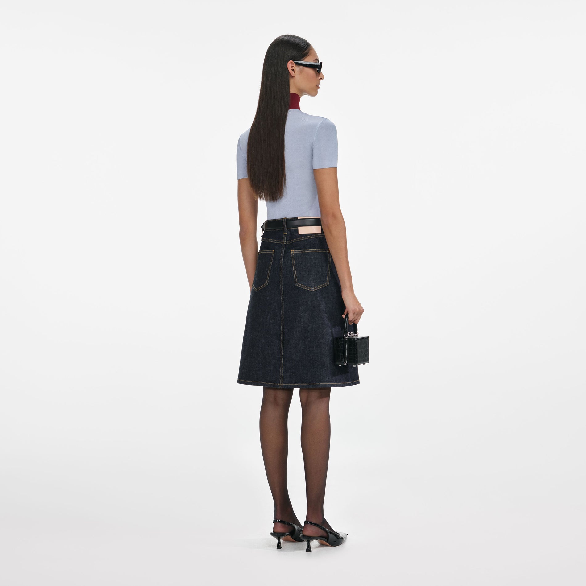 Back view of a woman wearing the Indigo Denim Belted Midi Skirt