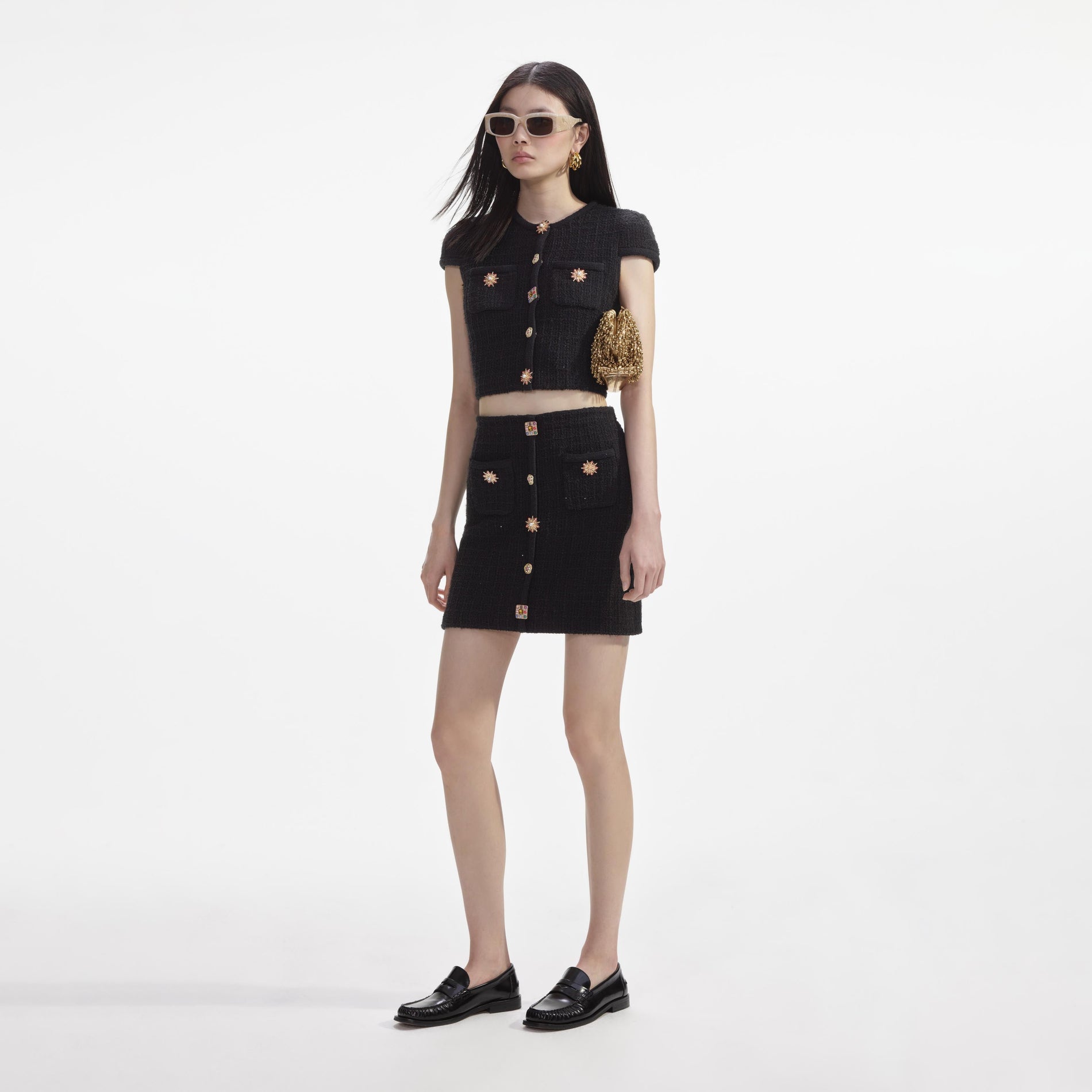 Side view of a woman wearing the Black Jewel Button Knit Mini Skirt
