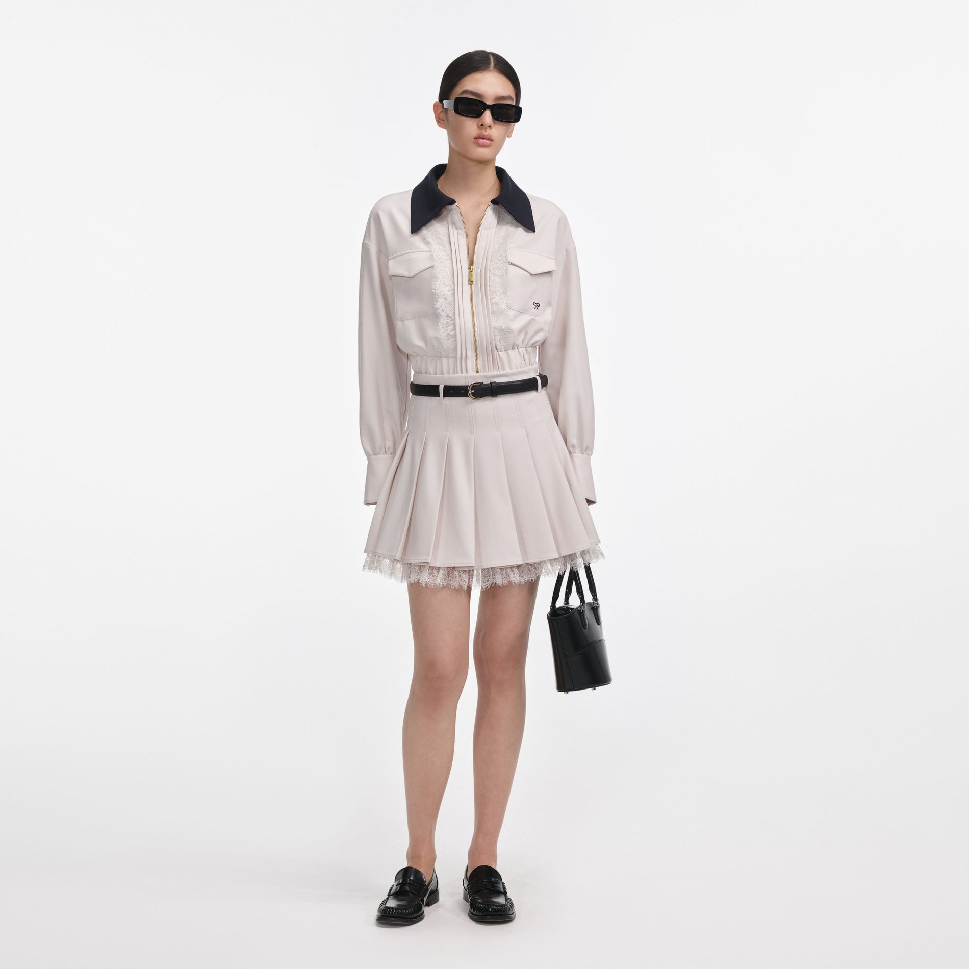 Front view of a woman wearing the Cream Twill Pleated Mini Skirt