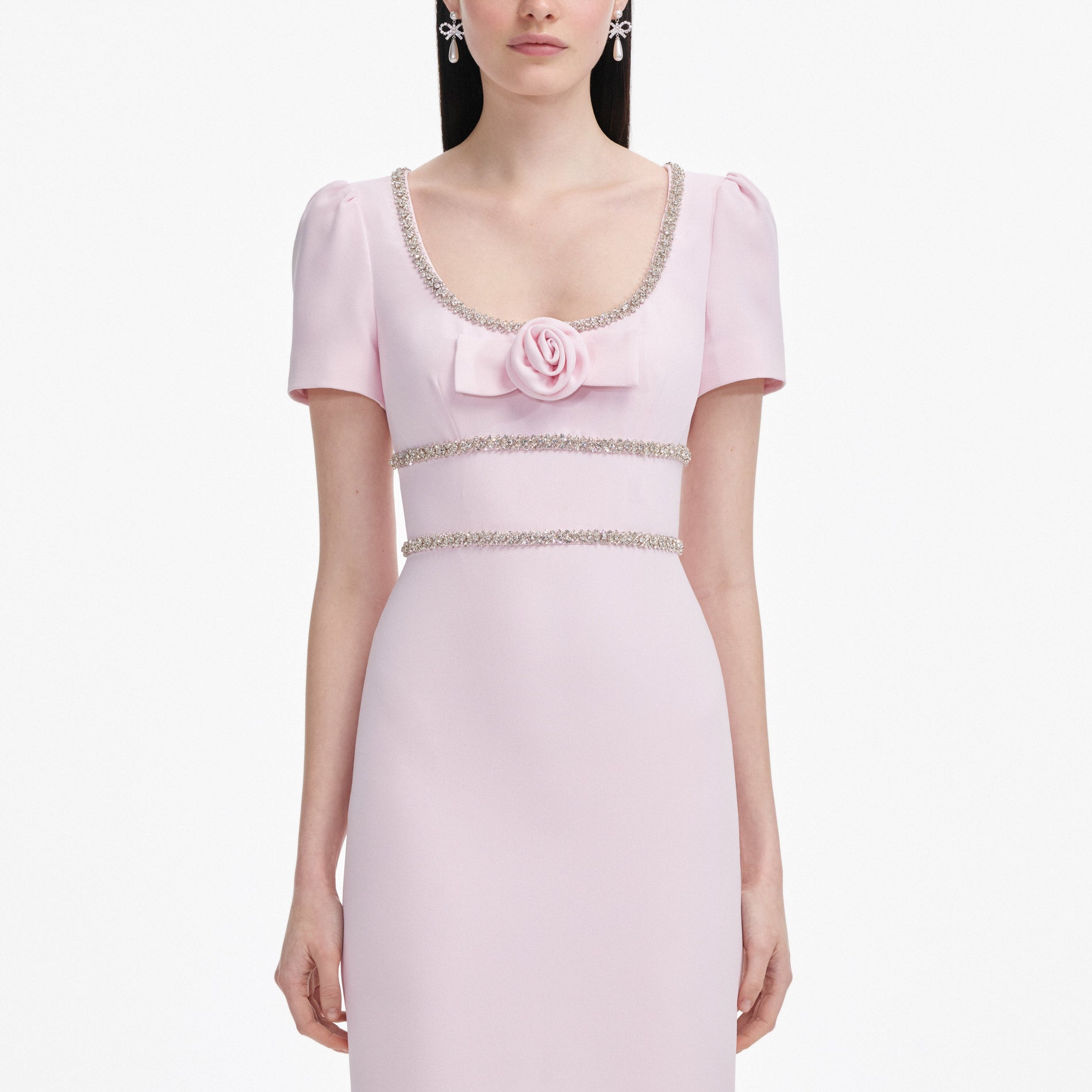 A close up of a woman wearing the Pink Crepe Crystal Trim Maxi Dress