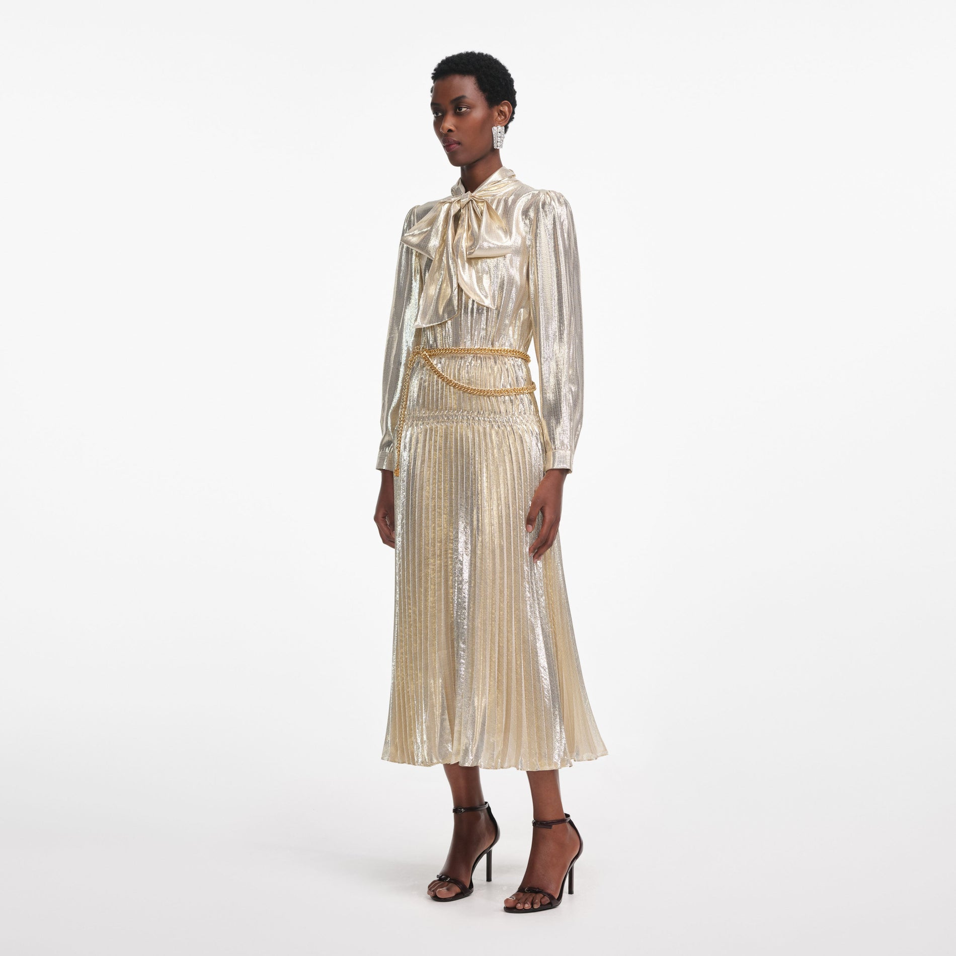 Side view of a woman wearing the Gold Metallic Pussy Bow Midi Dress