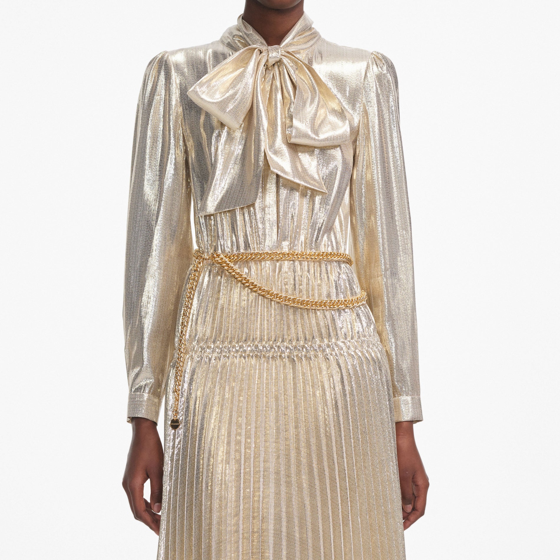 A close up of a woman wearing the Gold Metallic Pussy Bow Midi Dress