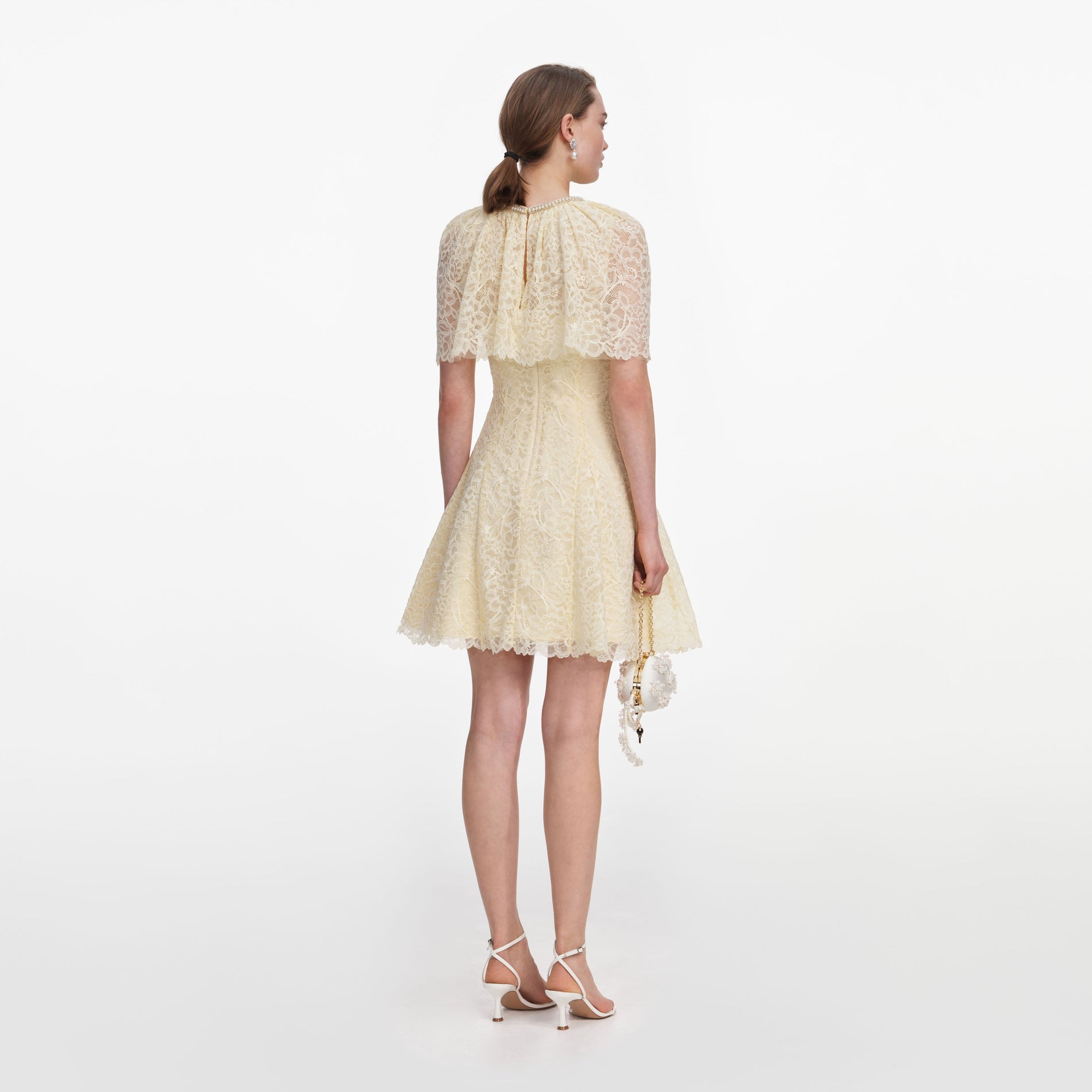 Back view of a woman wearing the Yellow Lace Cape Mini Dress