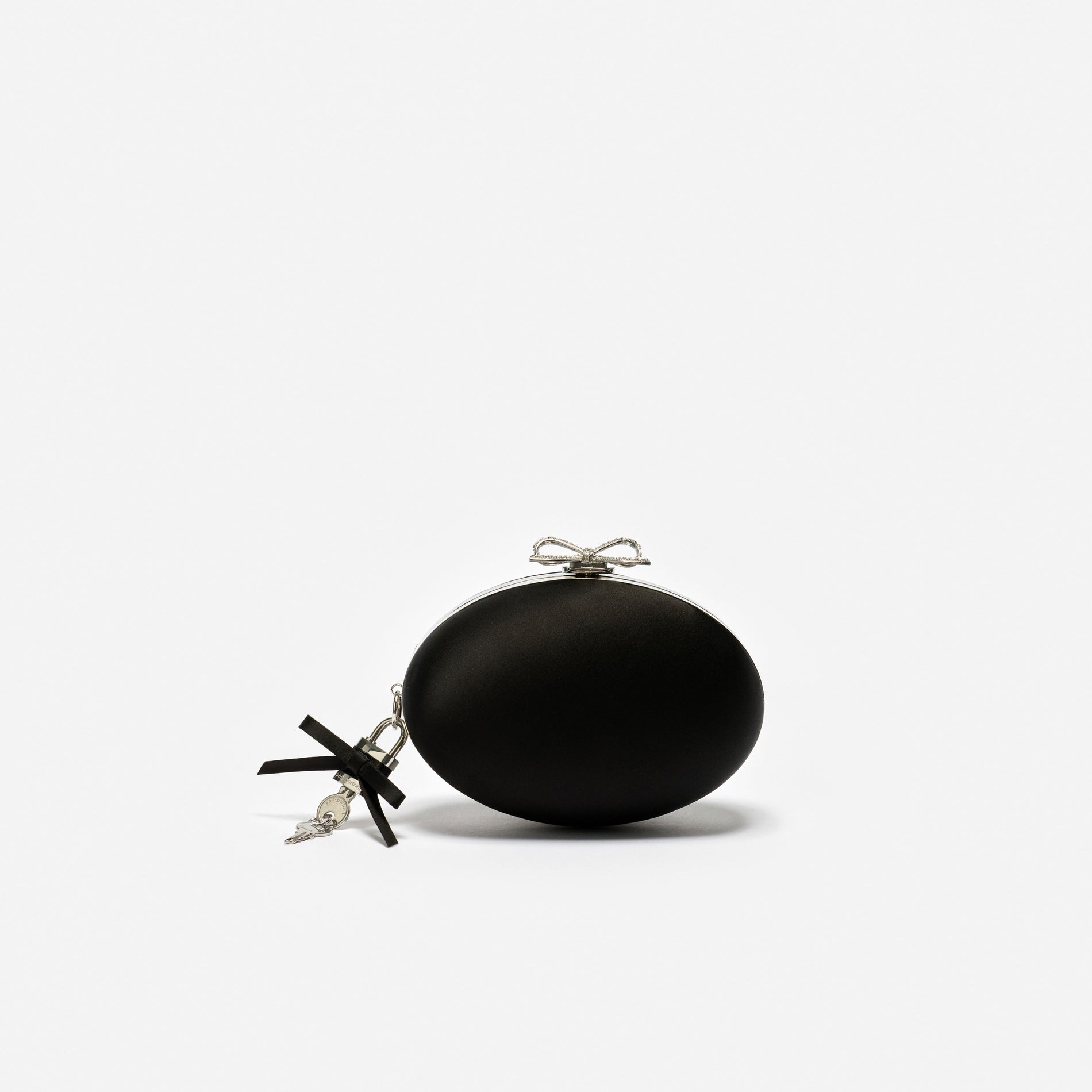 Black oval clutch bag with a silver bow clasp and a black ribbon and key charm