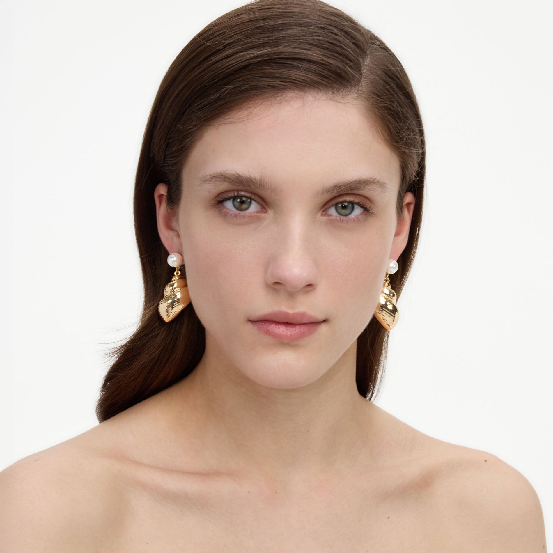 A close up of a woman wearing the Pearl Gold Shell Earrings