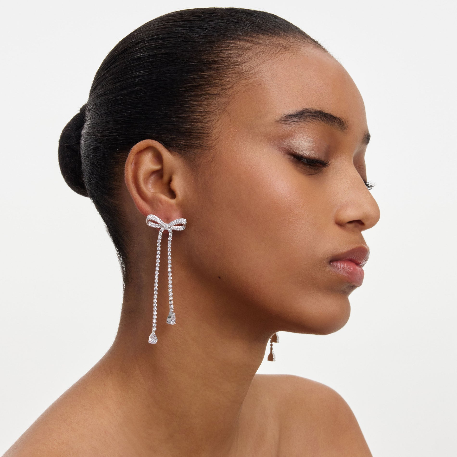 A close up of a woman wearing the Crystal Bow Dangle Earring