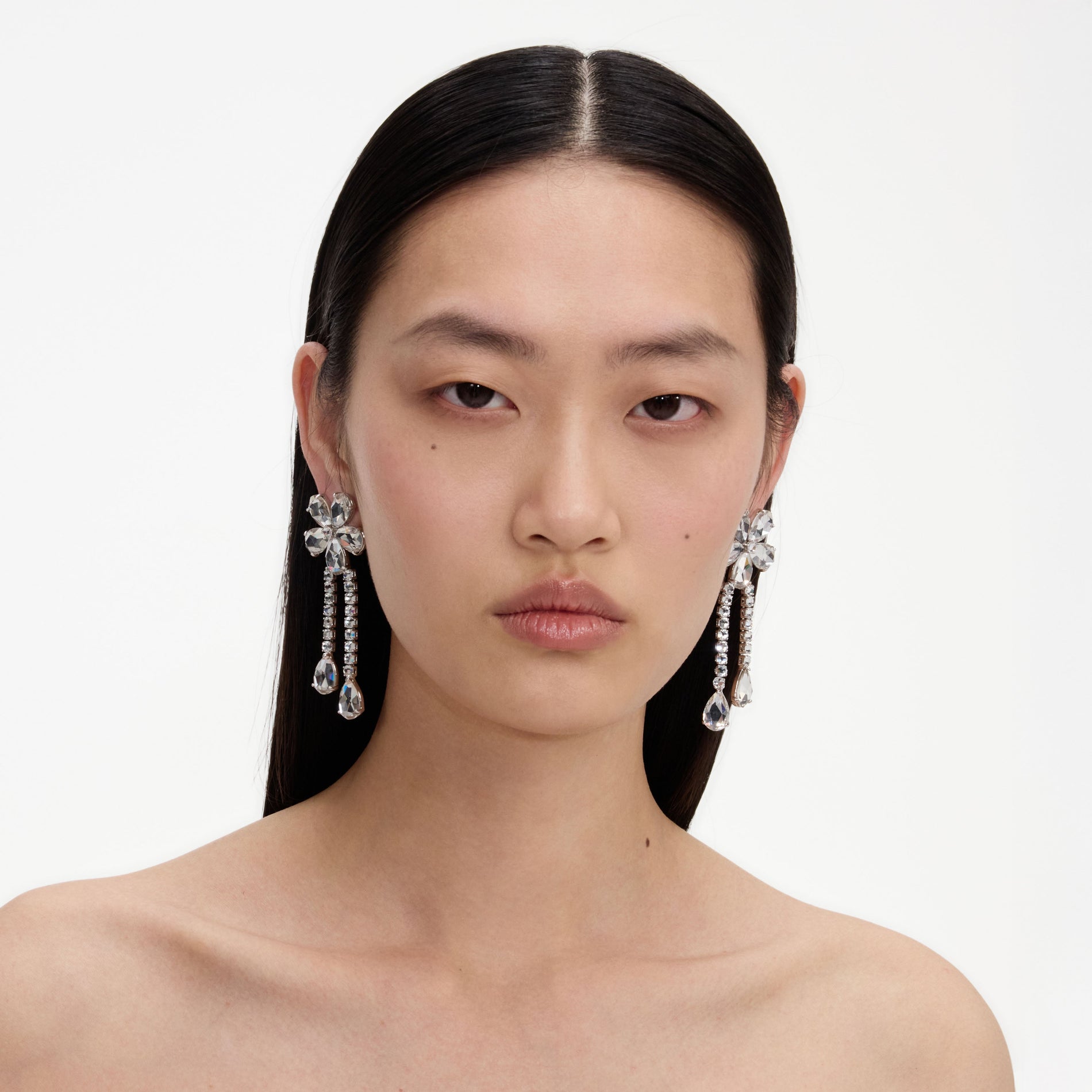 A close up of a woman wearing the Crystal Flower Droplet Earrings