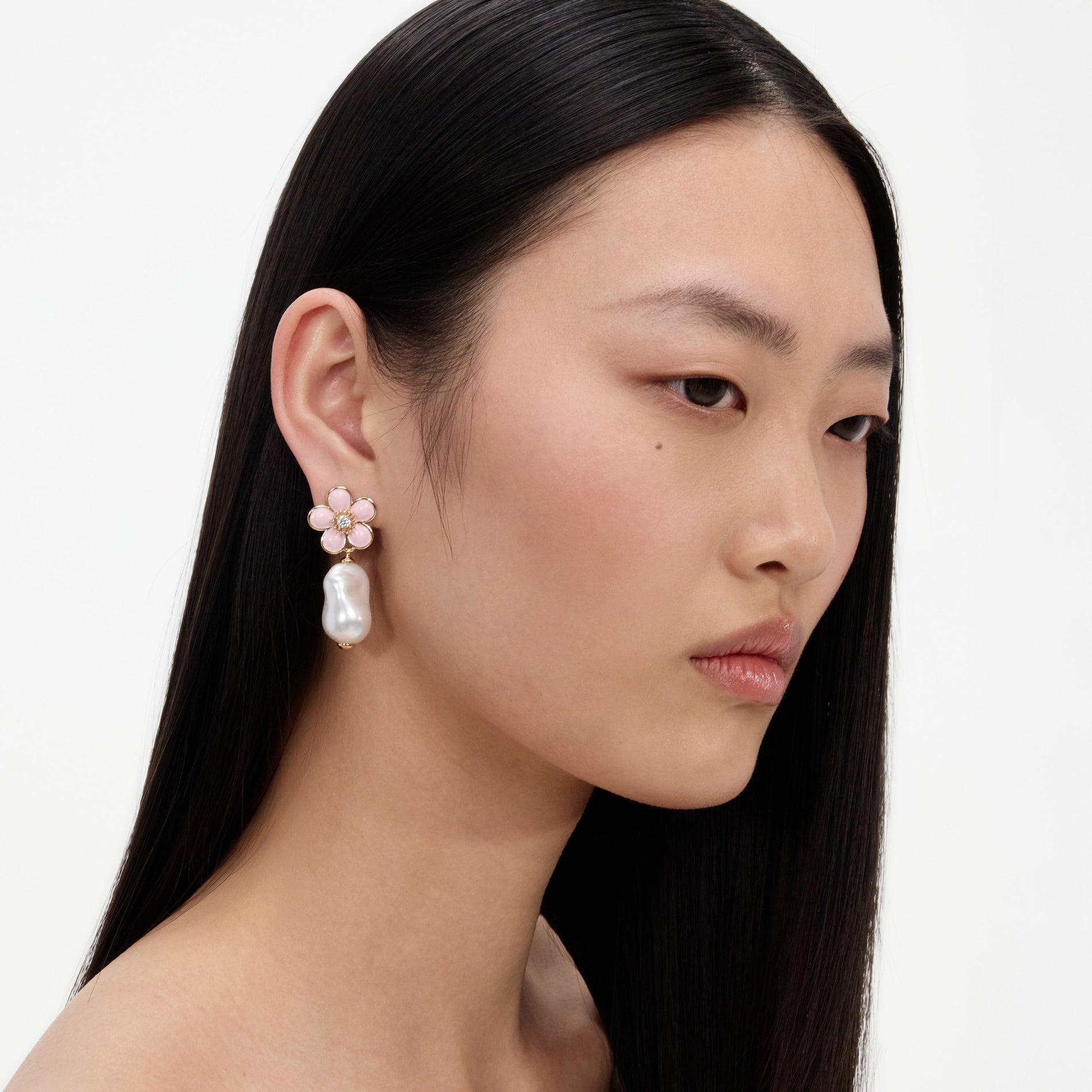 A close up of a woman wearing the Pink Flower Pearl Drop Earrings
