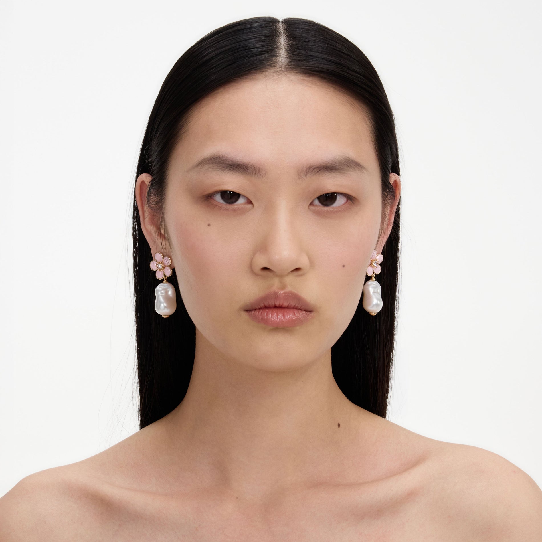 A close up of a woman wearing the Pink Flower Pearl Drop Earrings