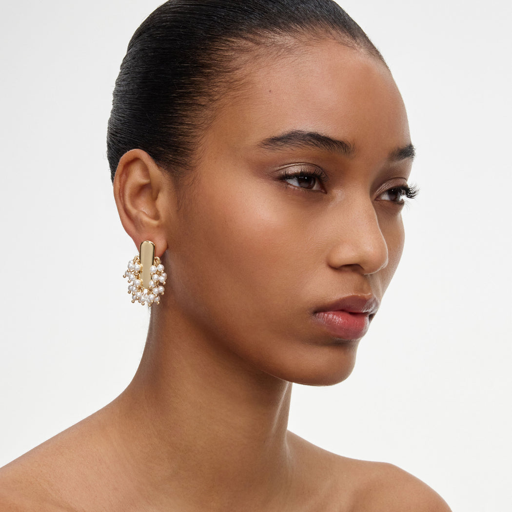 A close up of a woman wearing the Gold Pearl Cluster Earrings