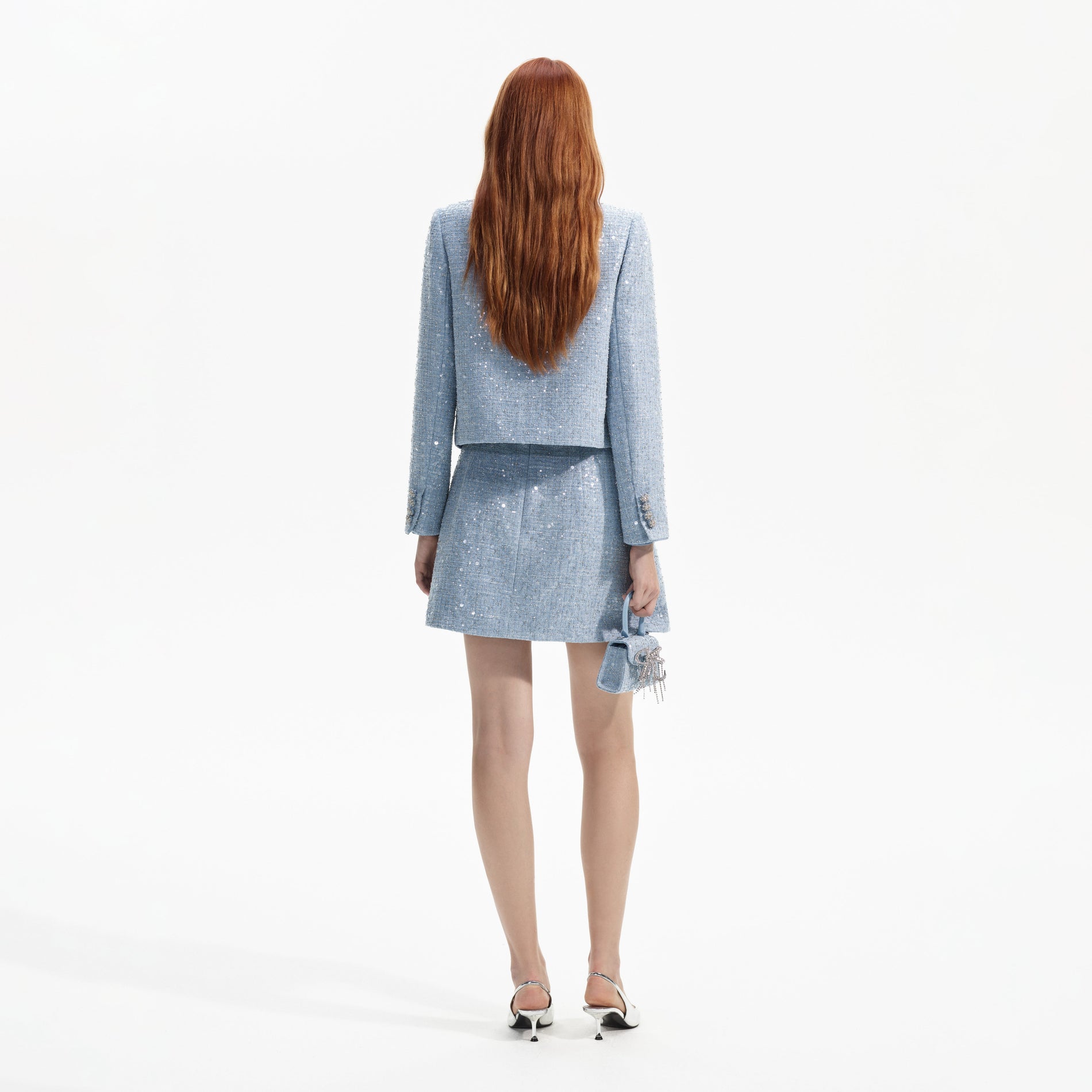 Back view of a woman wearing the Blue Sequin Boucle Jacket