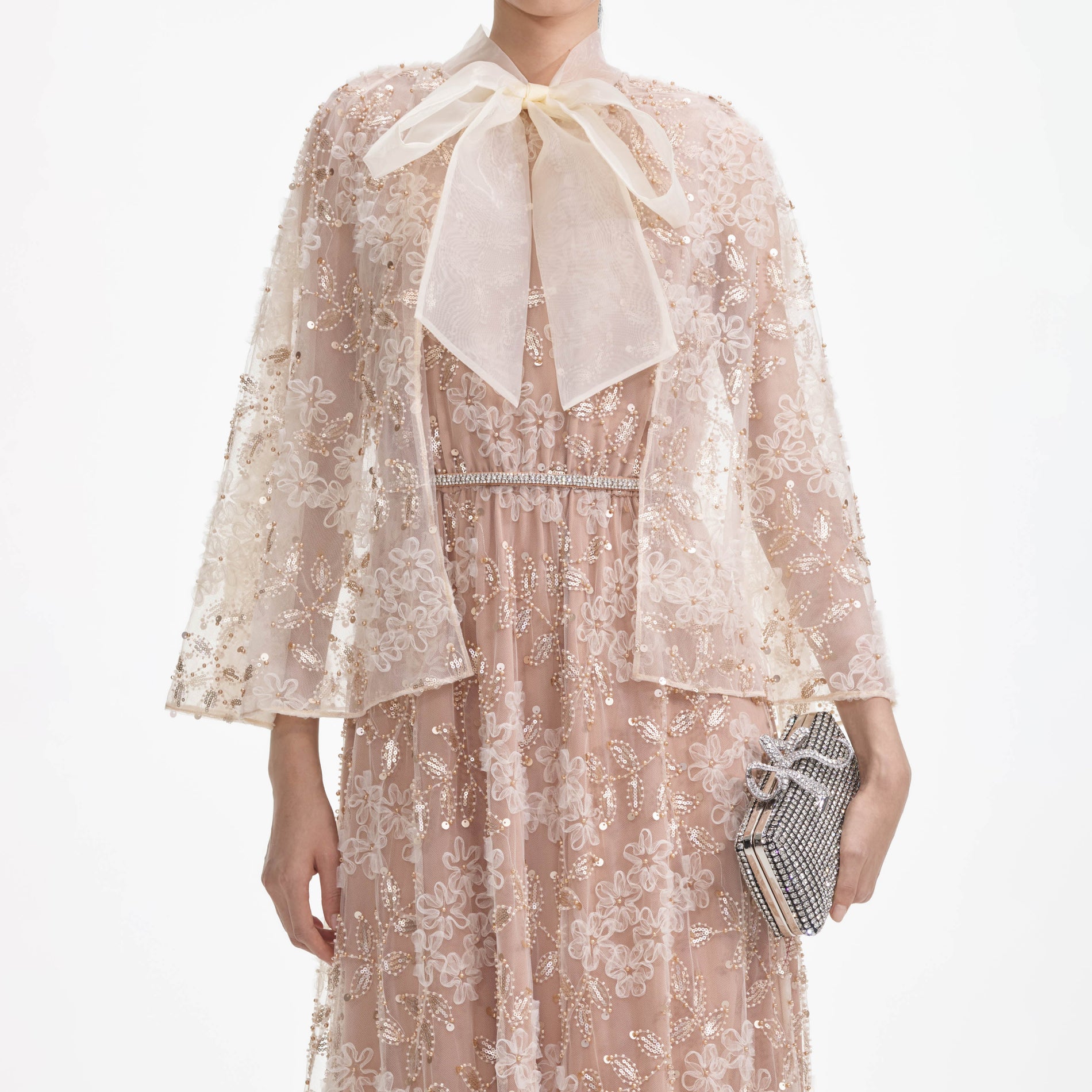 A close up of a woman wearing the Embellished Cape Maxi Dress