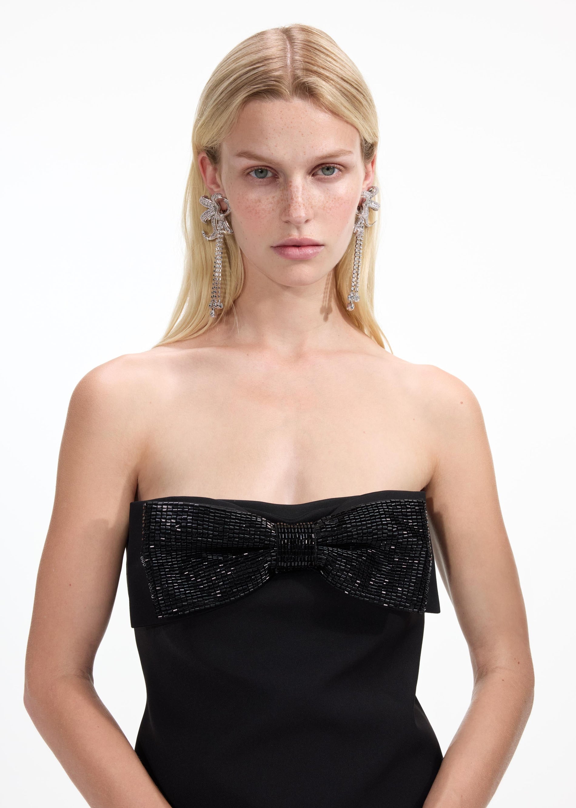 A close up of a woman wearing the Large Crystal Bow Droplet Earrings