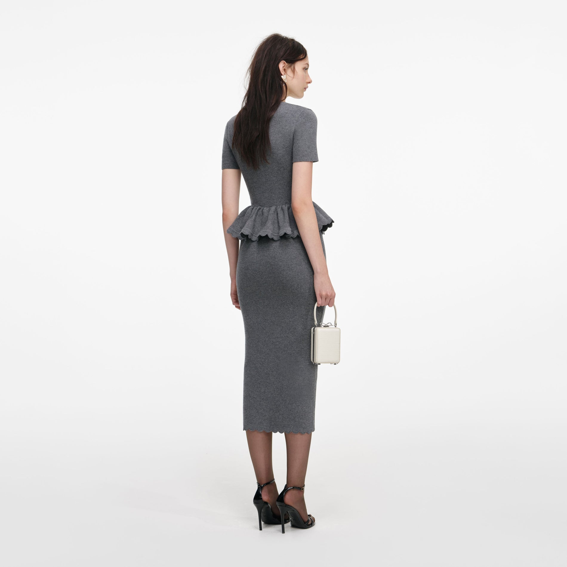 Back view of a woman wearing the Grey Peplum Knit Midi Dress