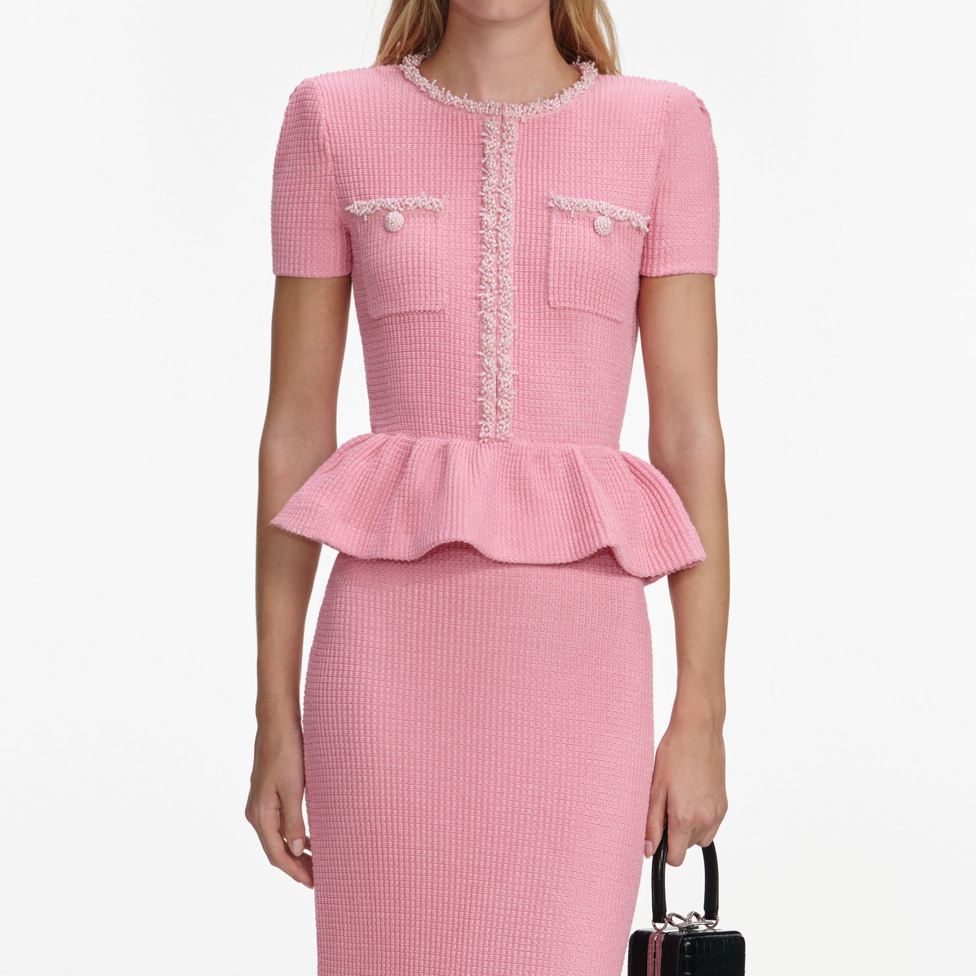 A close up of a woman wearing the Pink Peplum Knit Midi Dress