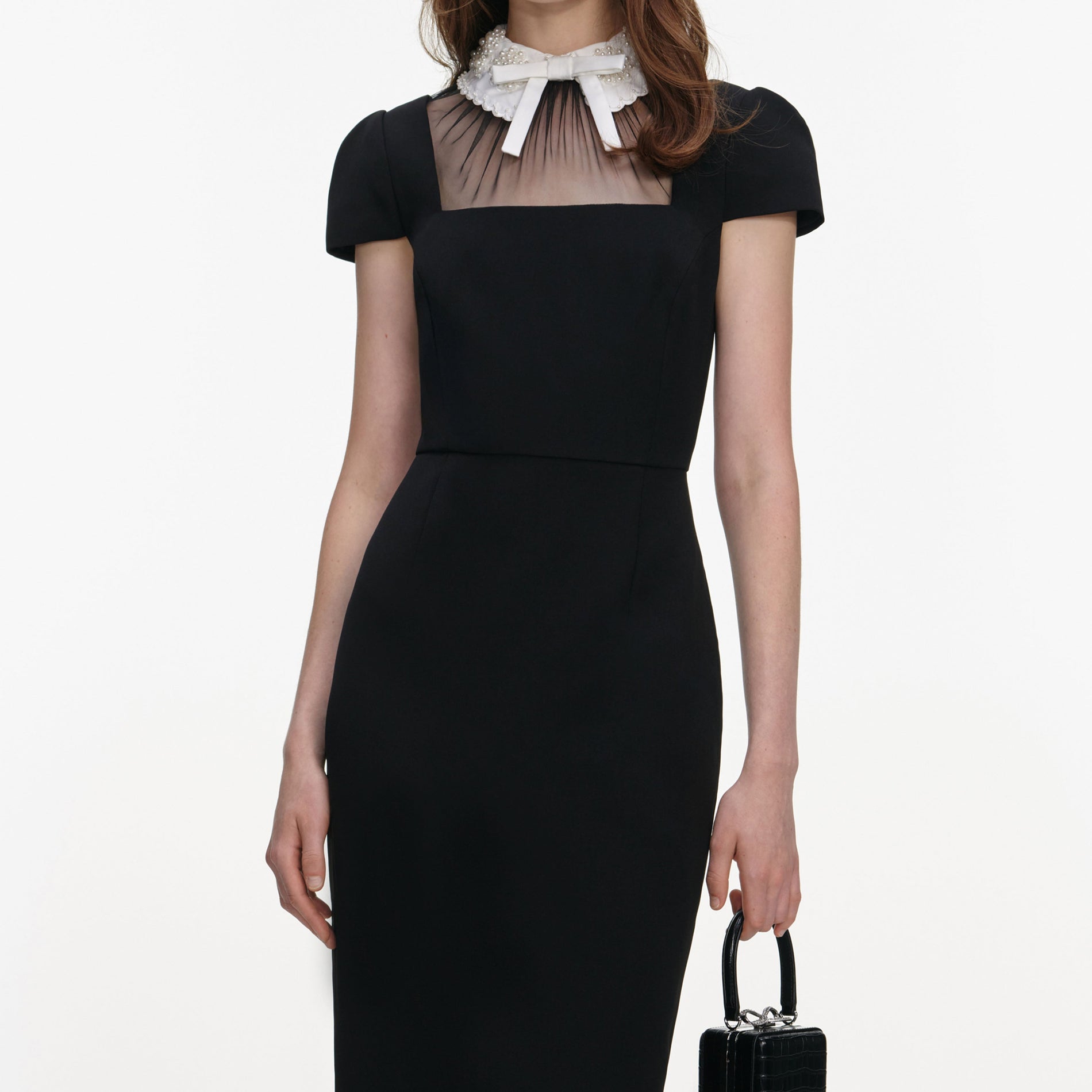 A close up of a woman wearing the Black Crepe Bow Collar Midi Dress