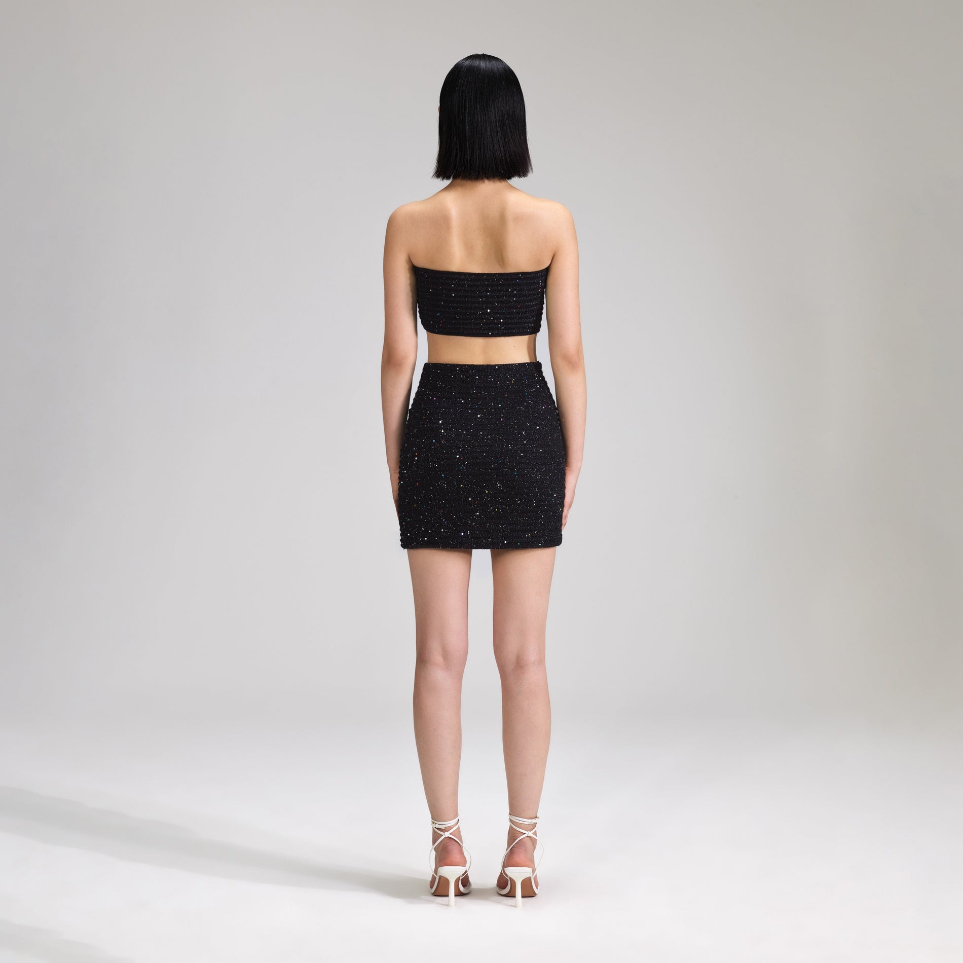 A woman wearing the Black Sequin Knit Bandeau Top