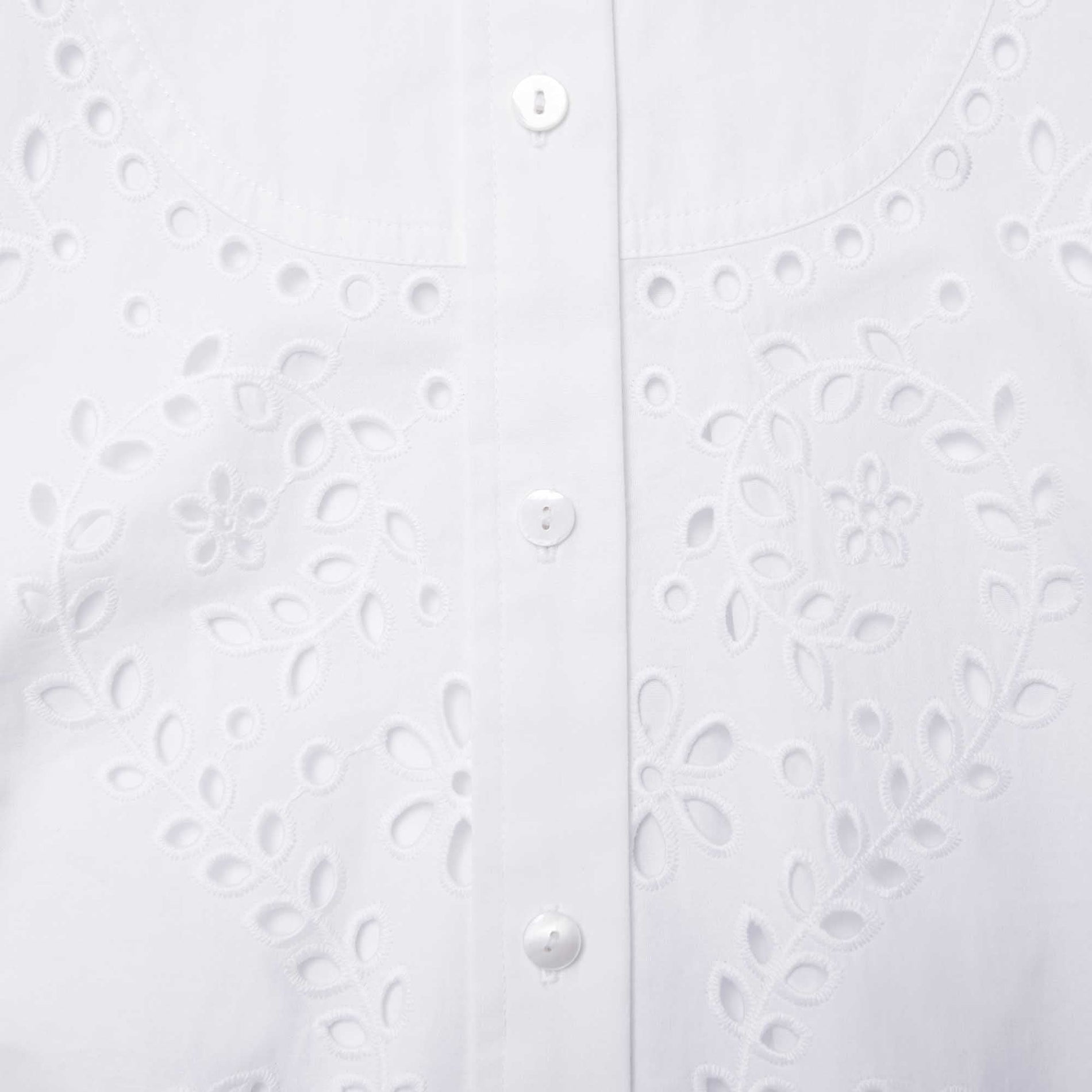A close up of a woman wearing the White Cotton Embroidered Shirt Dress