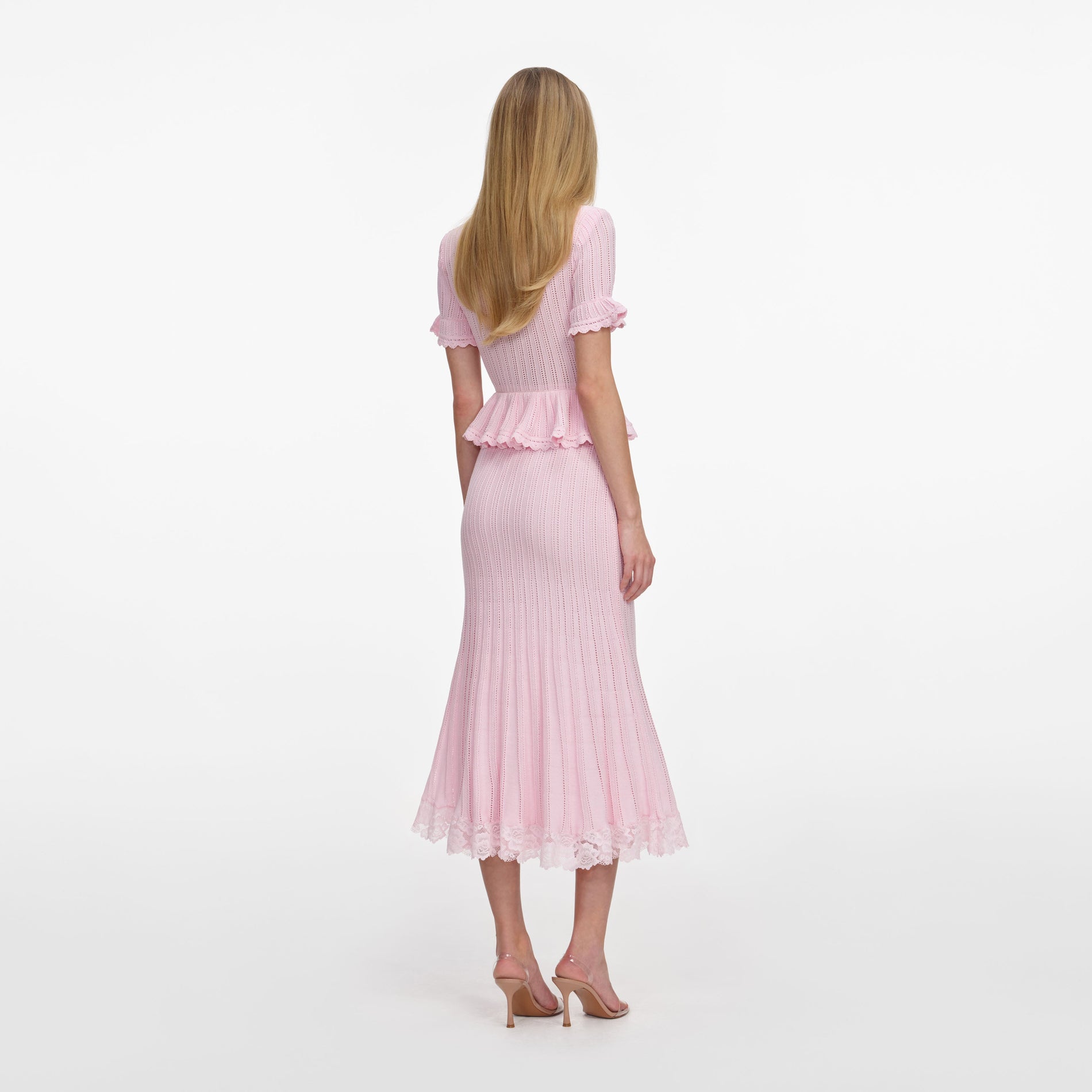 Back view of a woman wearing the Pink Pointelle Peplum Knit Midi Dress