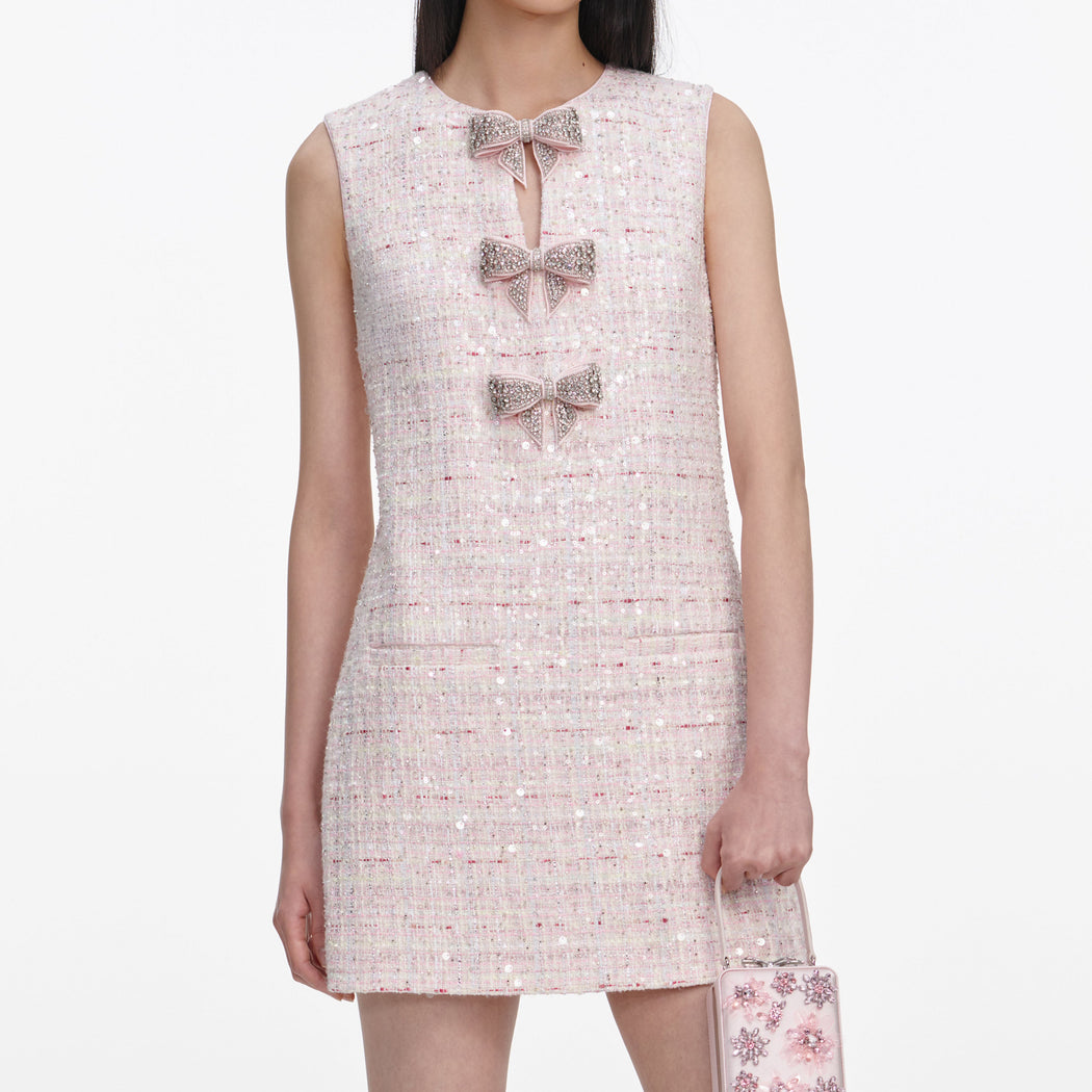A close up of a woman wearing the Pink Sequin Boucle Bow Mini Dress