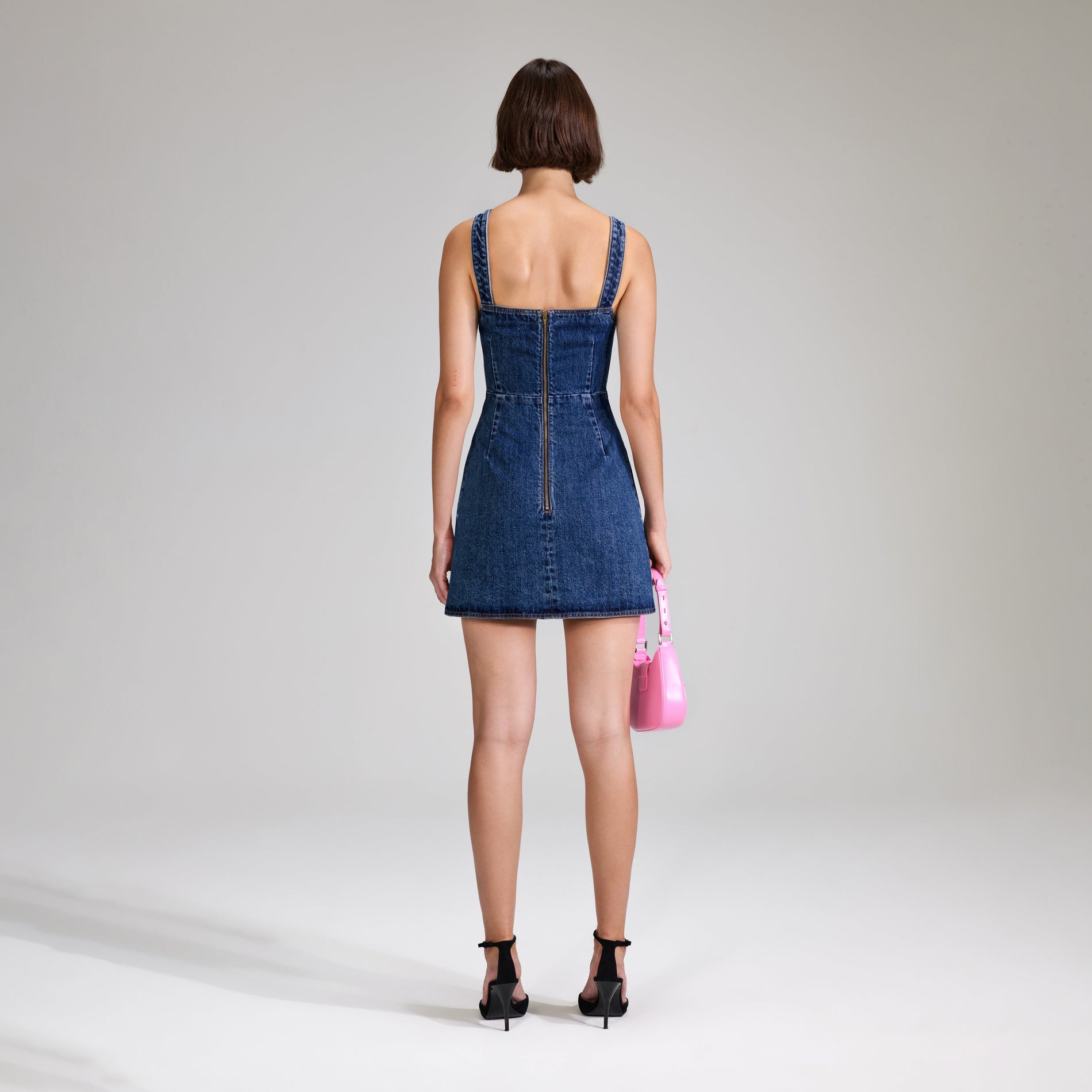 A woman wearing the Denim Mini Dress With Bows