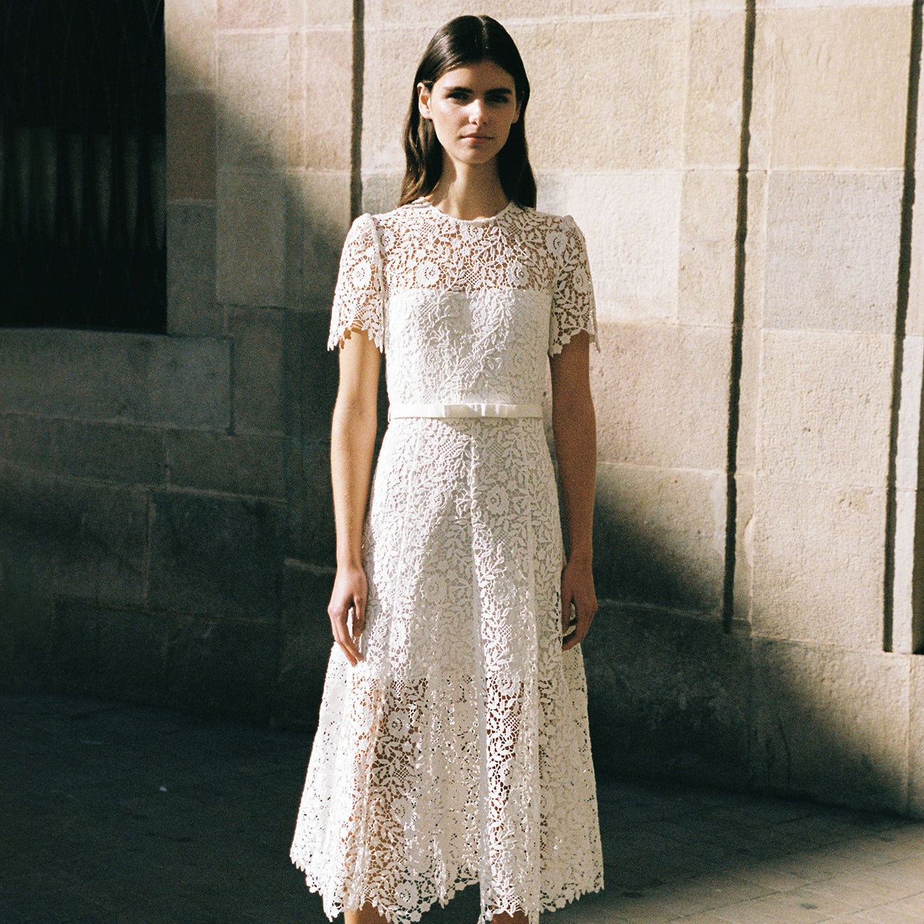 A woman wearing the White Rose Lace Midi Dress