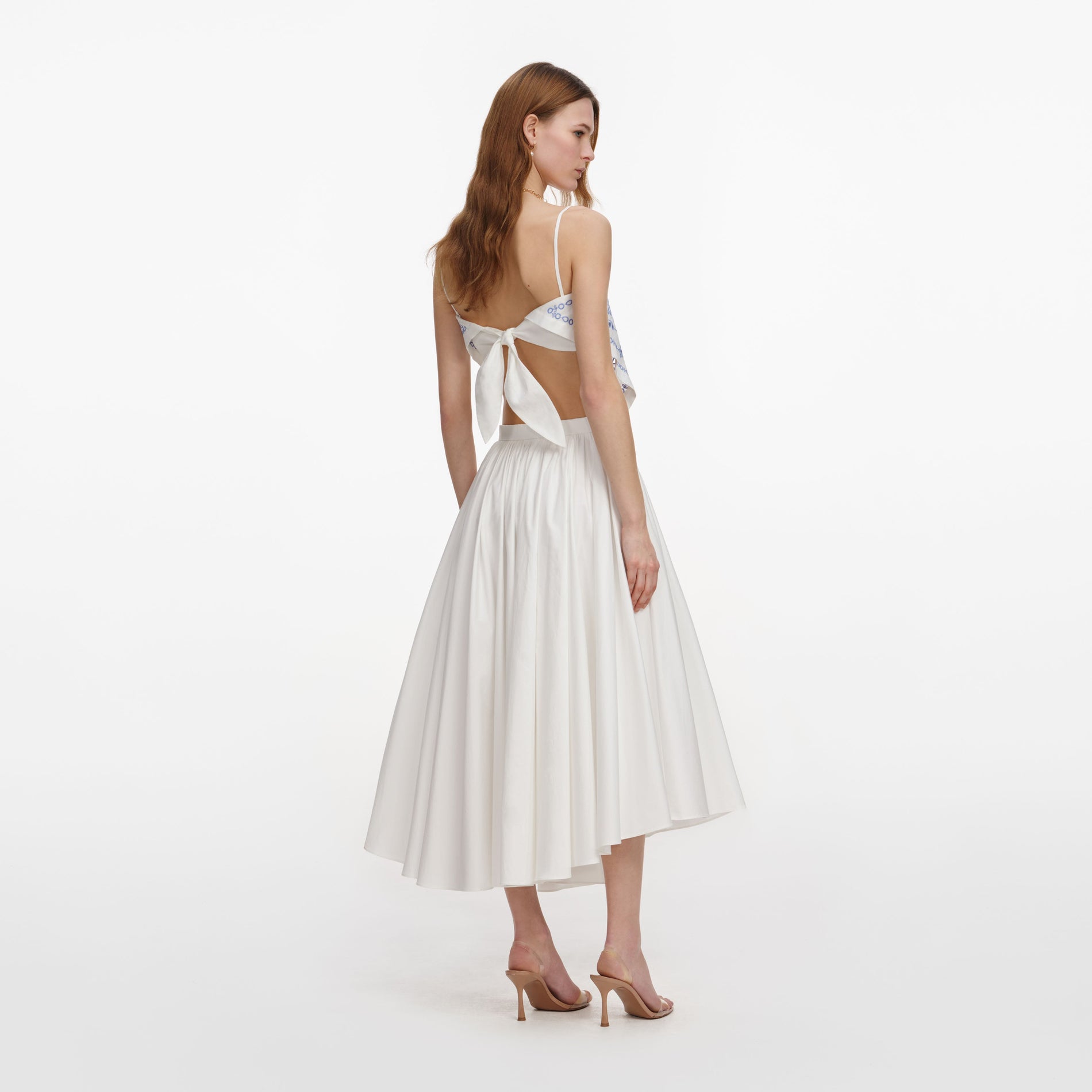 Back view of a woman wearing the White And Blue Embroidered Linen Top