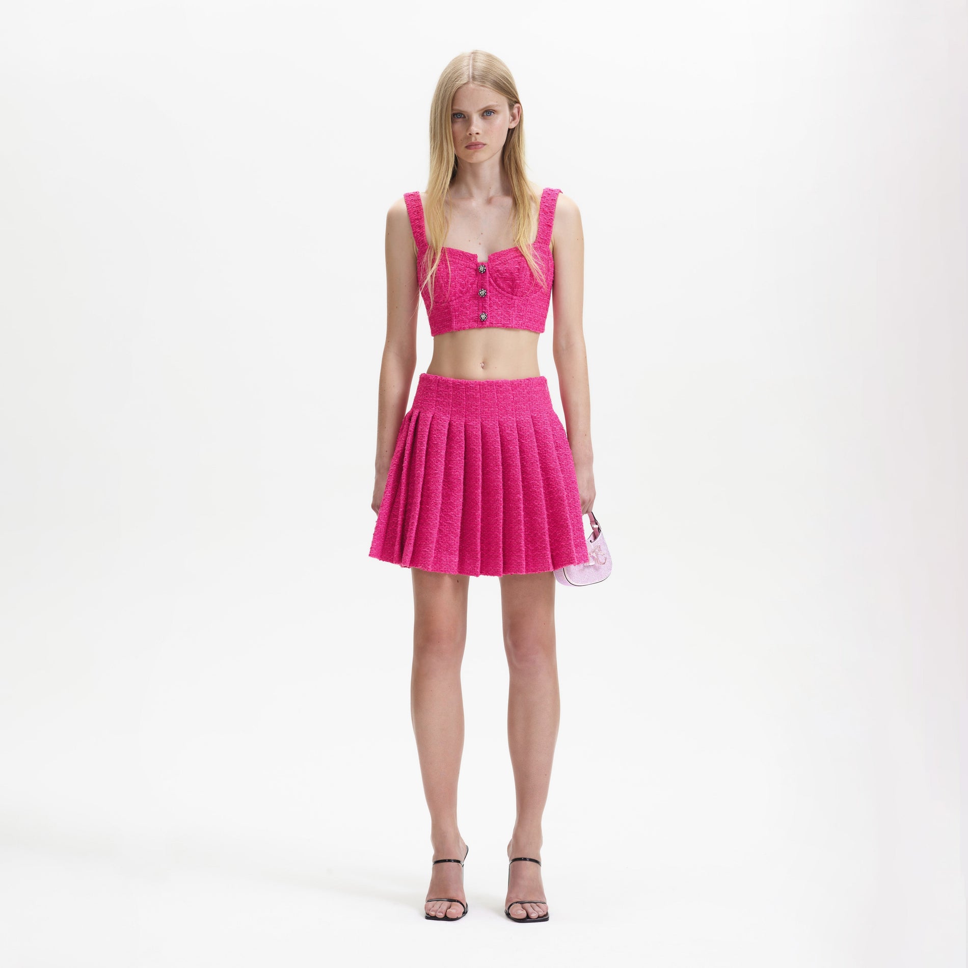 A woman wearing the Fuchsia Boucle Pleated Mini Skirt