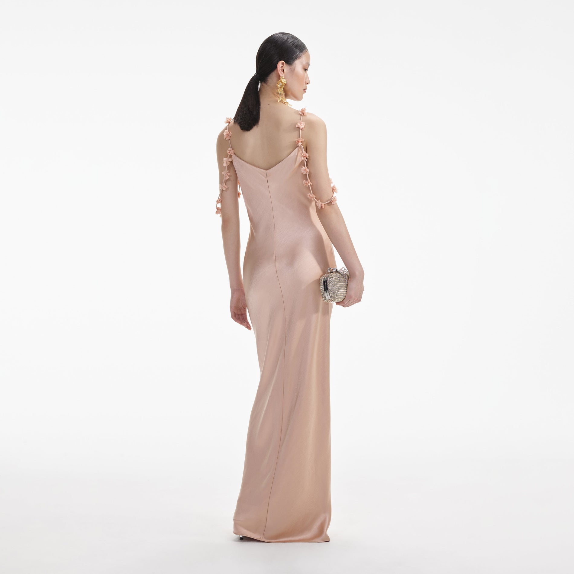 Back view of a woman wearing the White Rose Gold Satin Flower Maxi Dress