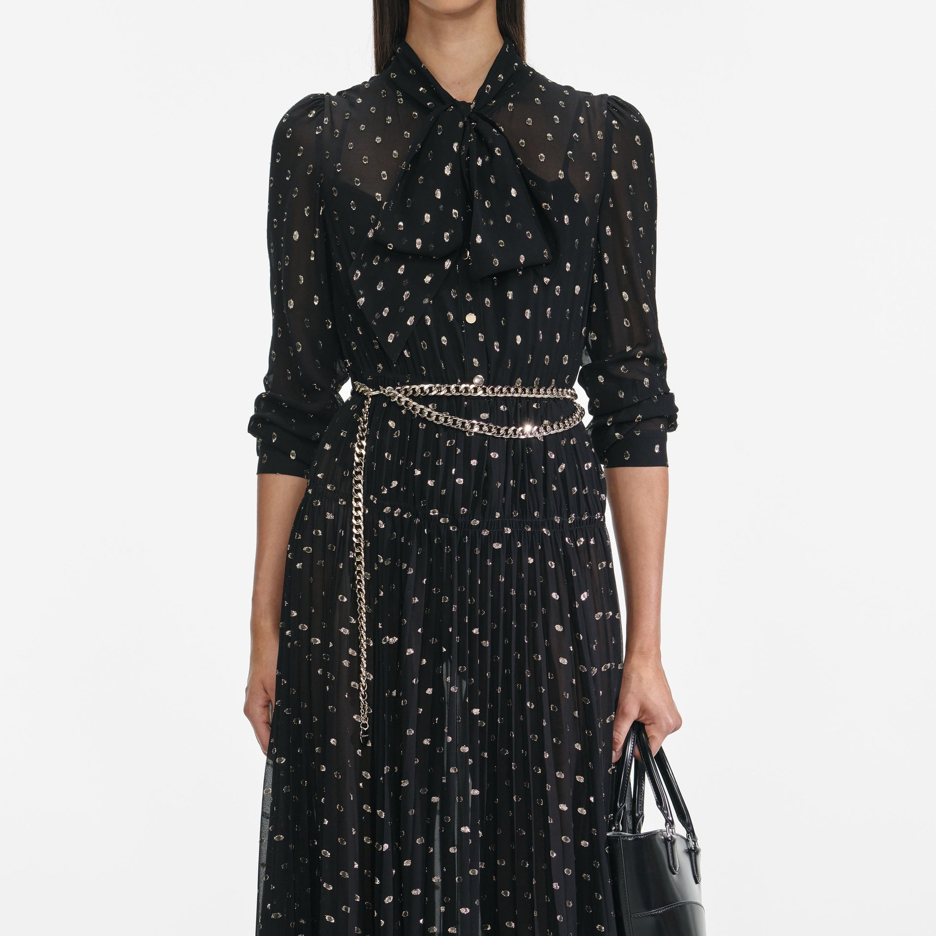 A close up of a woman wearing the Black And Gold Pussy Bow Maxi Dress