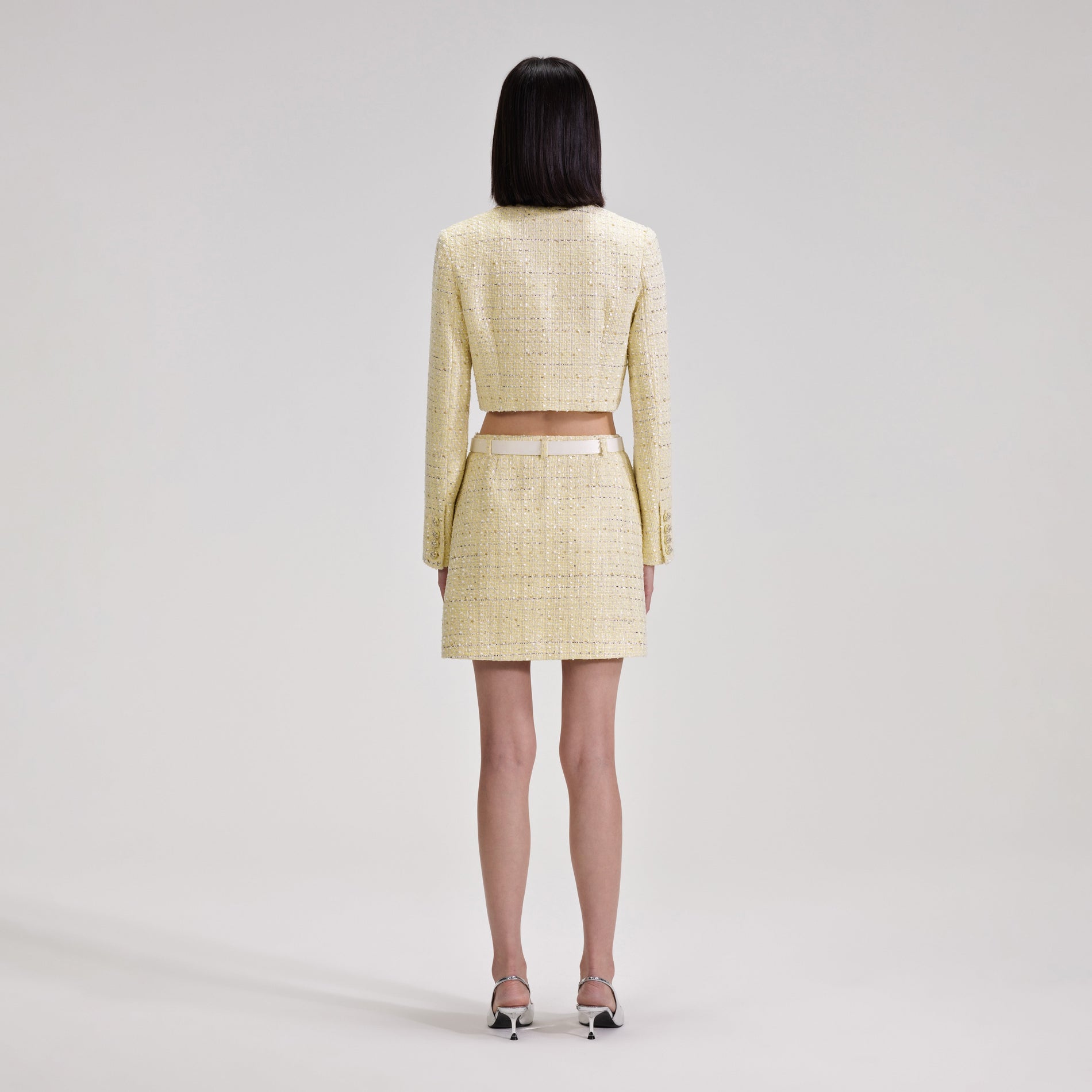 A woman wearing the Yellow Boucle Mini Skirt