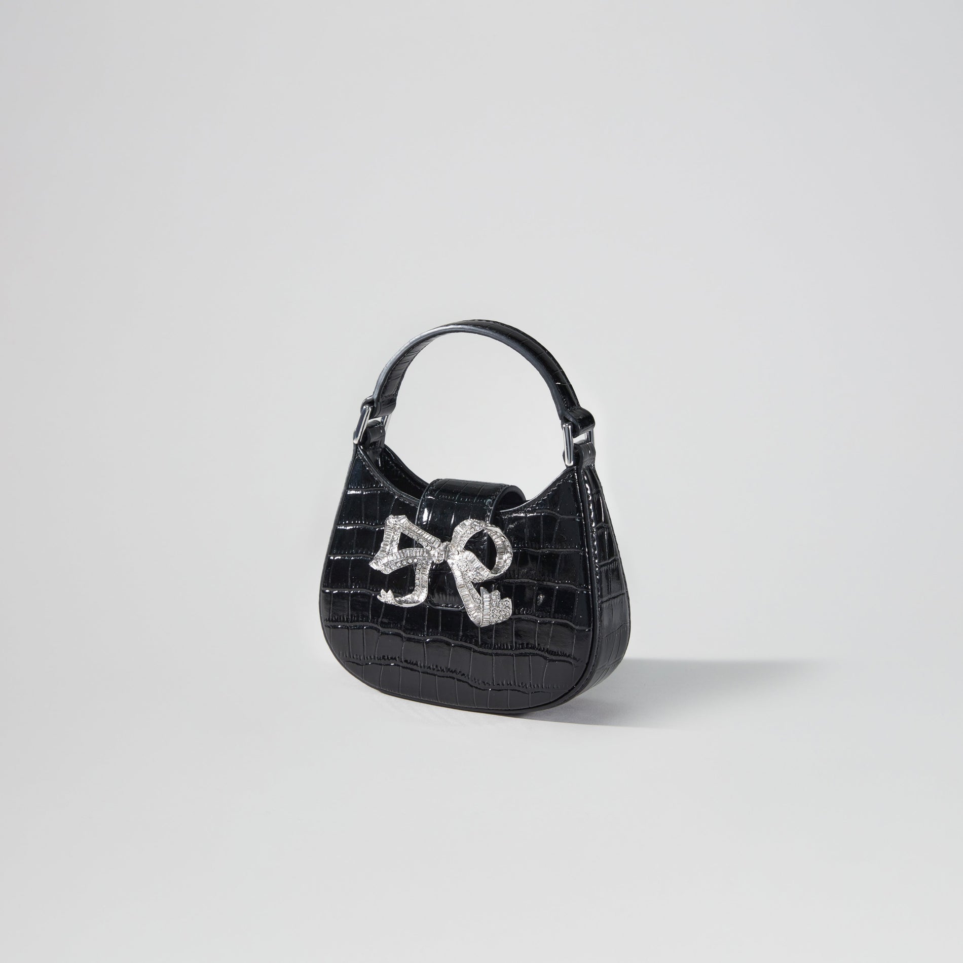 Side view of a woman wearing the Black Croc Crescent Bow Micro Bag