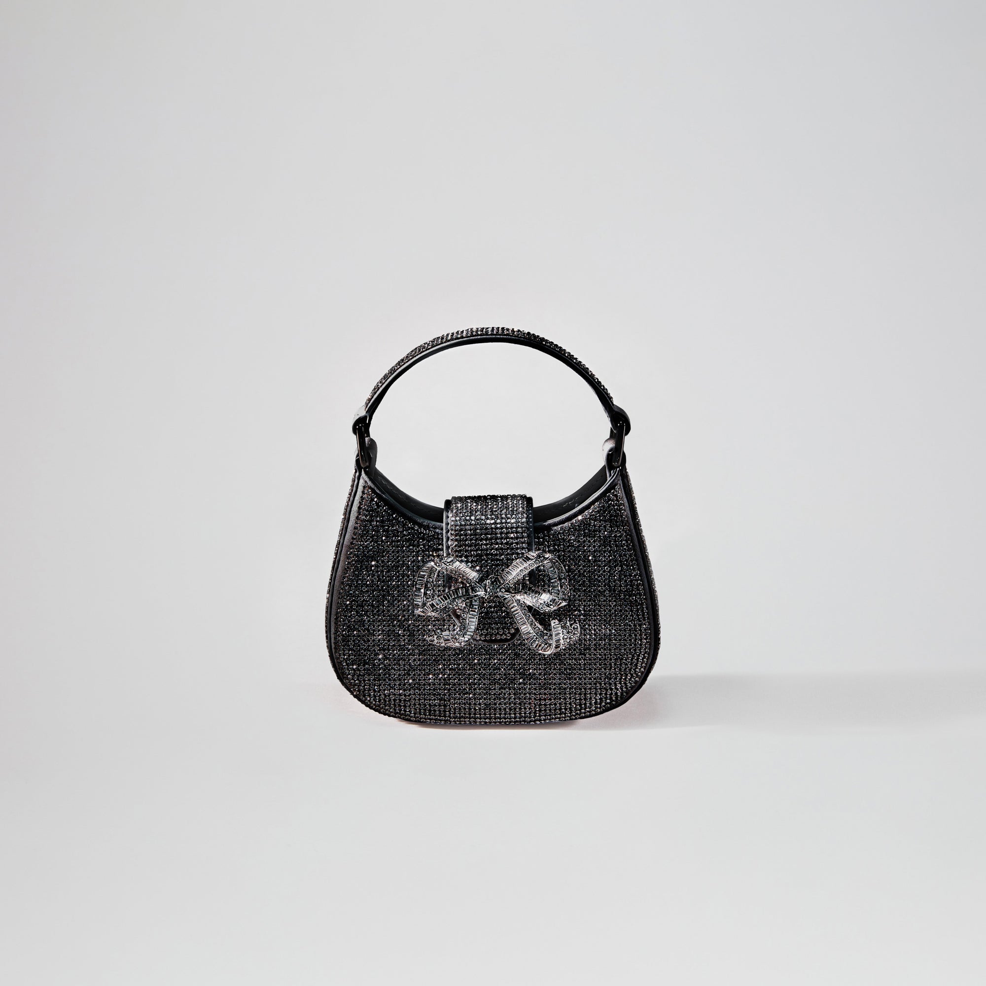 A woman wearing the Black Rhinestone Crescent Bow Micro Bag