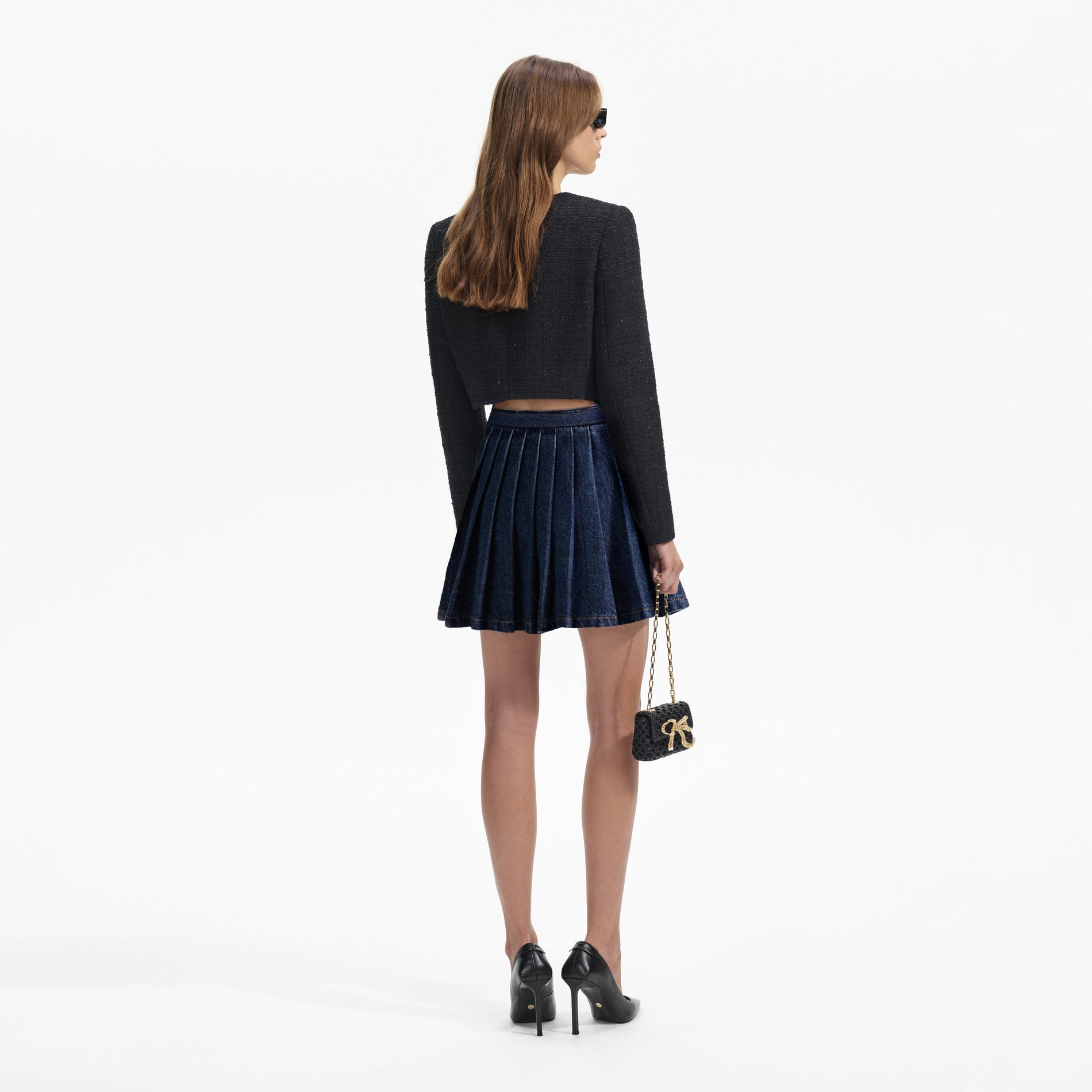 Back view of a woman wearing the Denim Pleated Mini Skirt