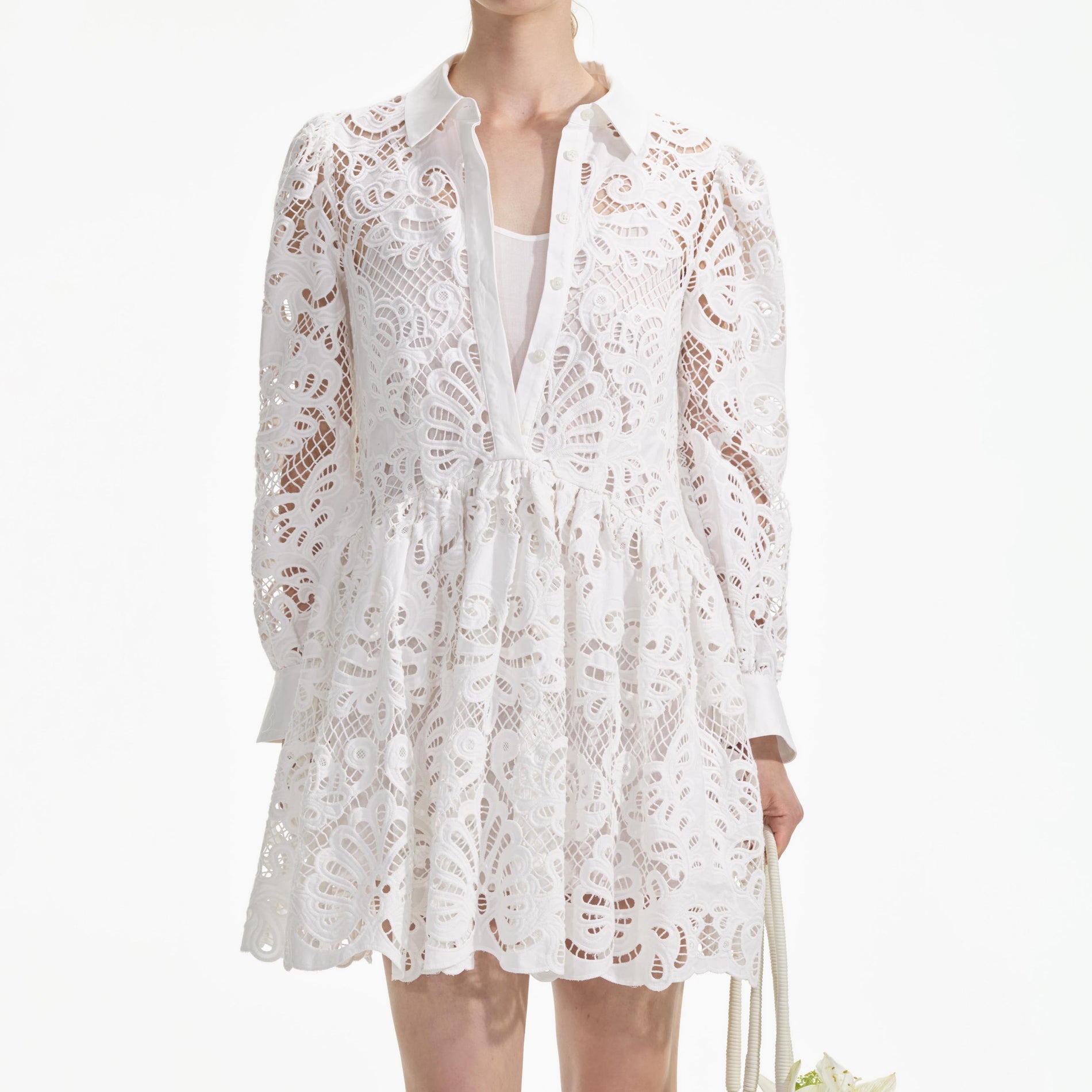 A close up of a woman wearing the White Cotton Lace Mini Shirt Dress