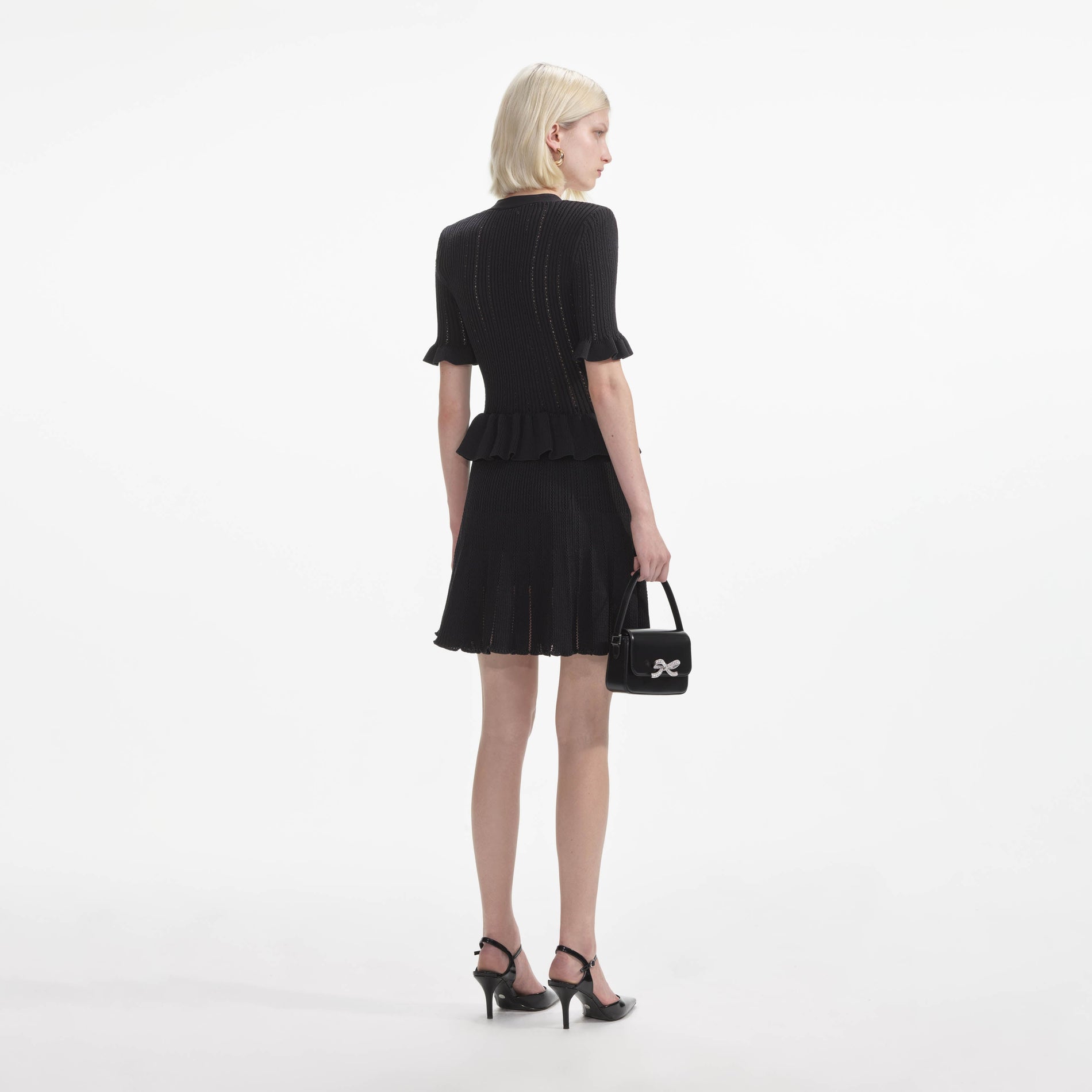 Back view of a woman wearing the Black Knit Peplum Mini Dress