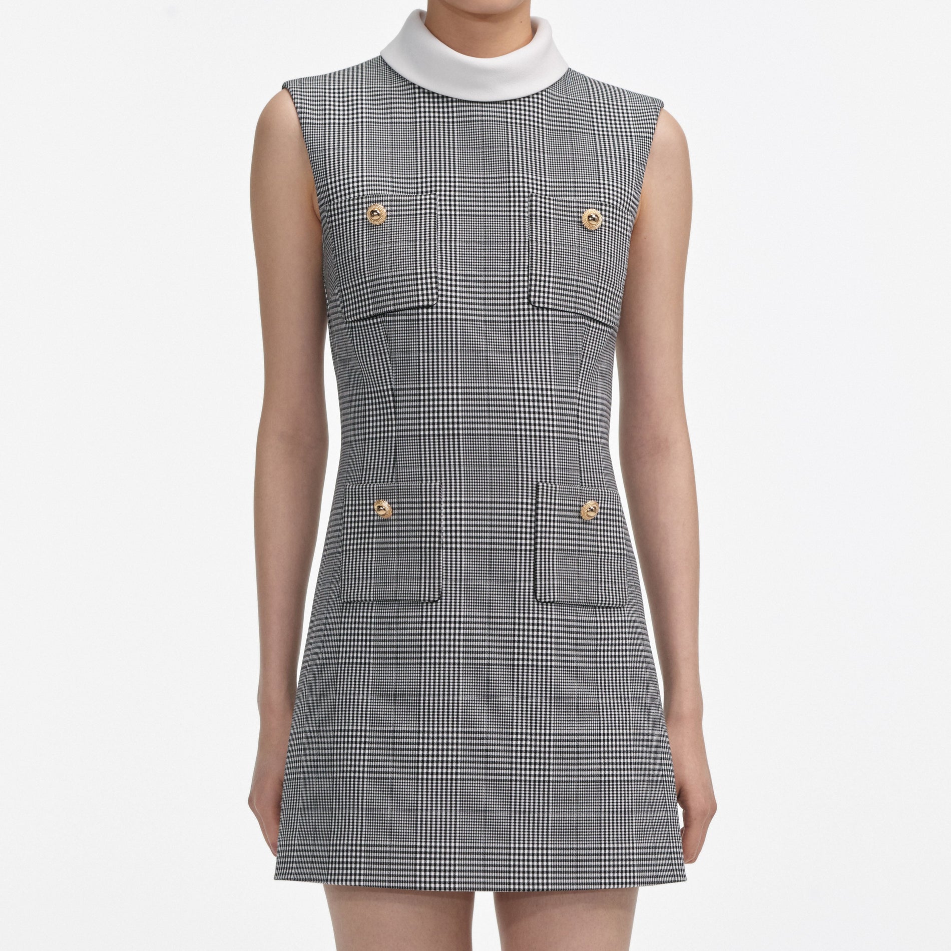 A close up of a woman wearing the Sleeveless Prince Of Wales Check Mini Dress