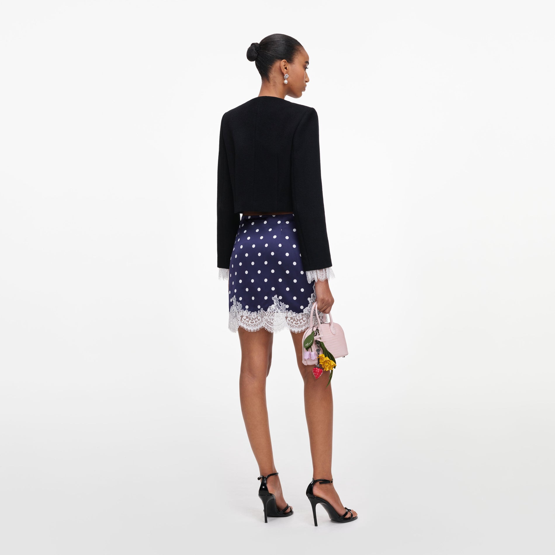 Back view of a woman wearing the Navy Polka Dot Satin Mini Skirt