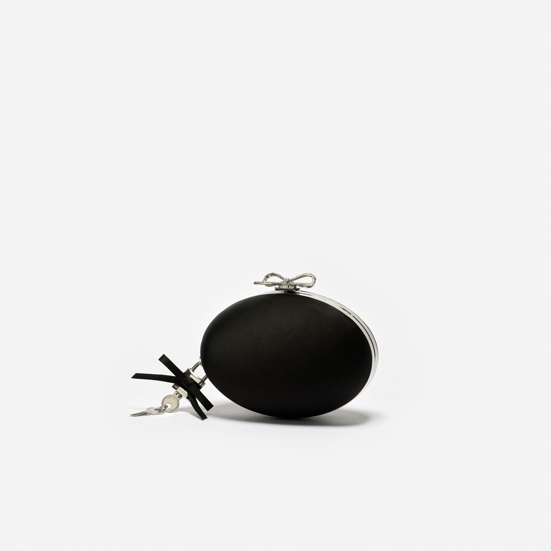 Black round clutch bag with a silver bow clasp and a small key charm