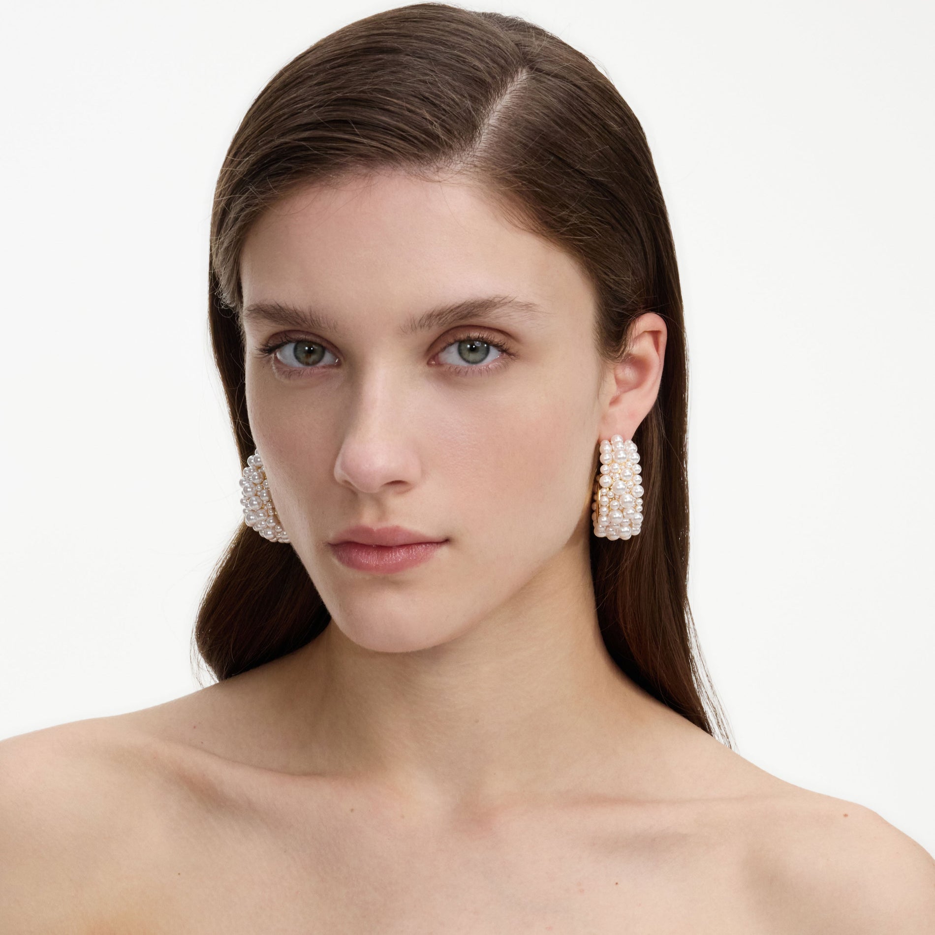 A close up of a woman wearing the Pearl Cluster Hoop Earrings