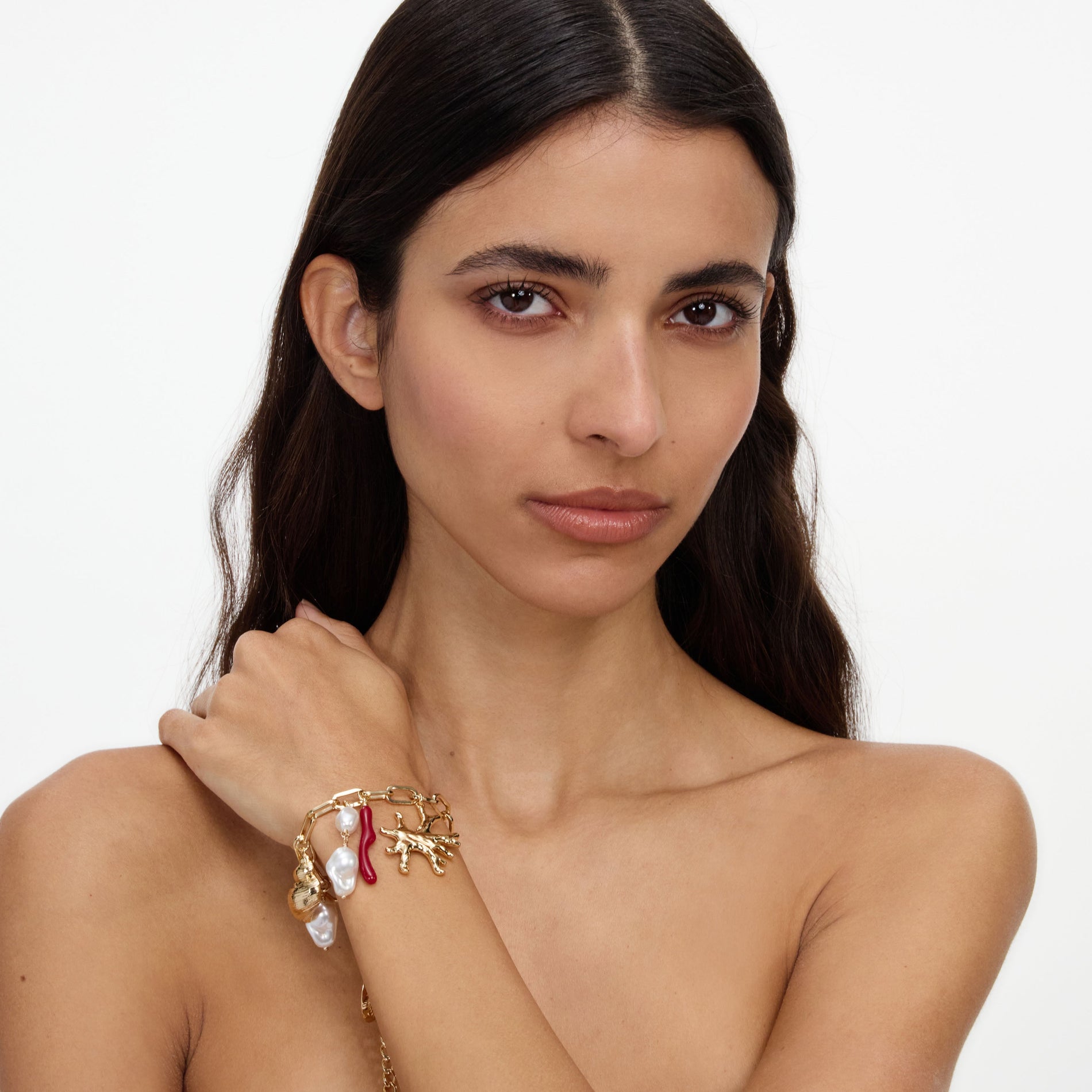 A close up of a woman wearing the Gold Coral Pearl Charm Bracelet