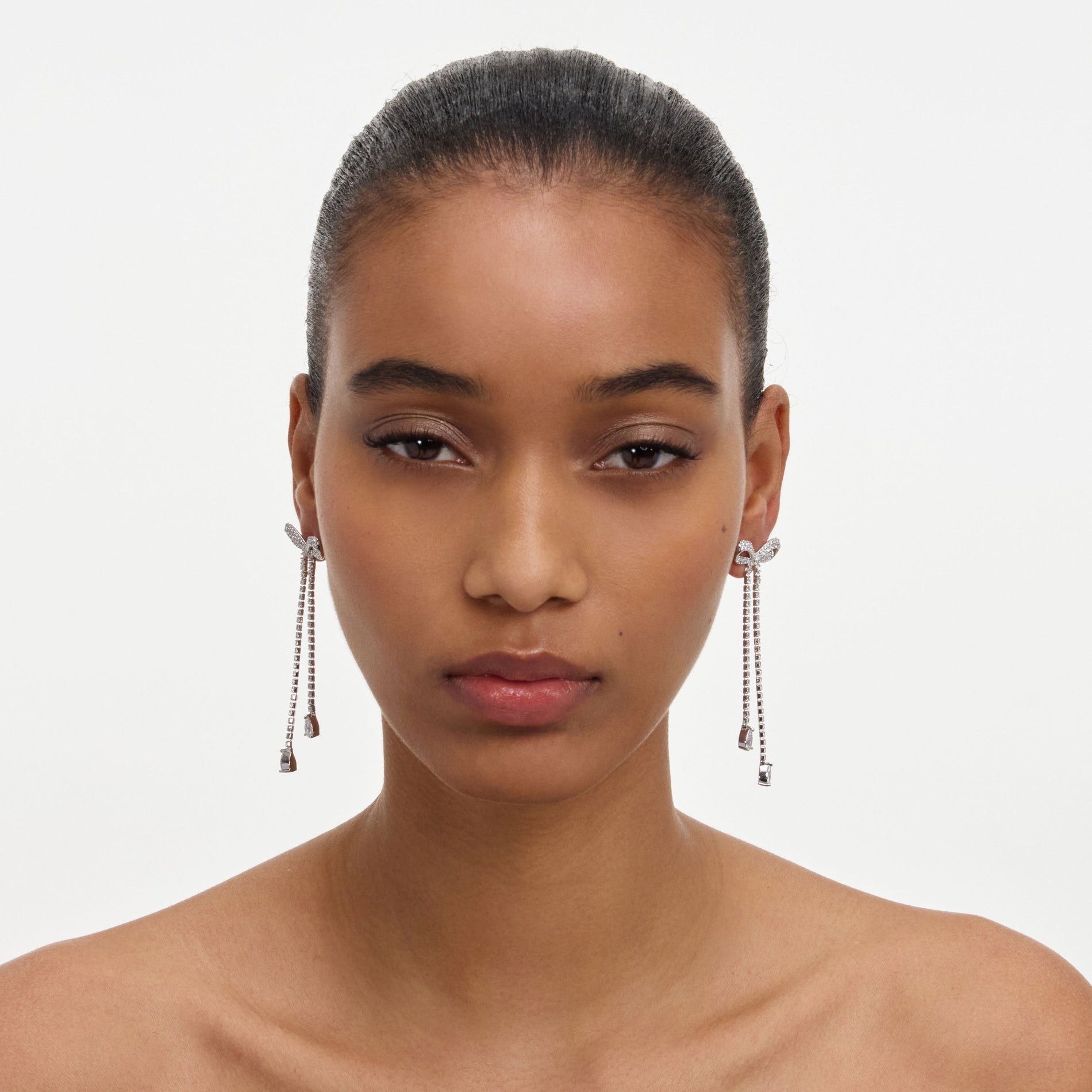 A close up of a woman wearing the Crystal Bow Dangle Earring