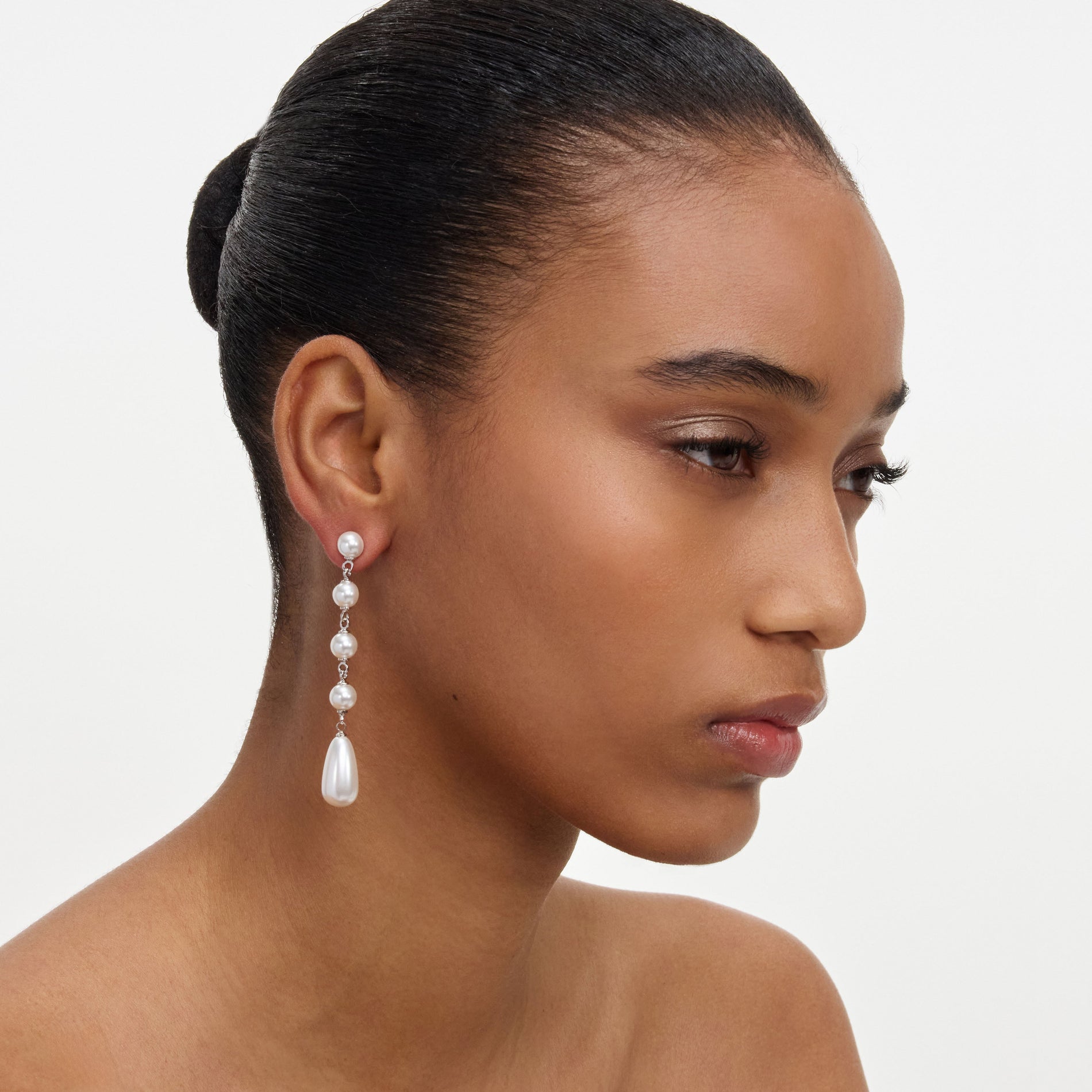 A close up of a woman wearing the Pearl Droplet Earrings