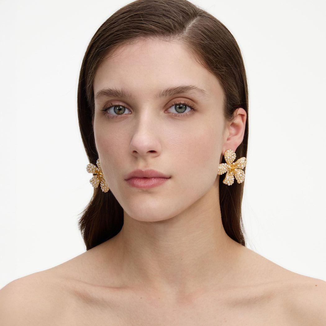 A close up of a woman wearing the Gold Pearl Encrusted Flower Earrings