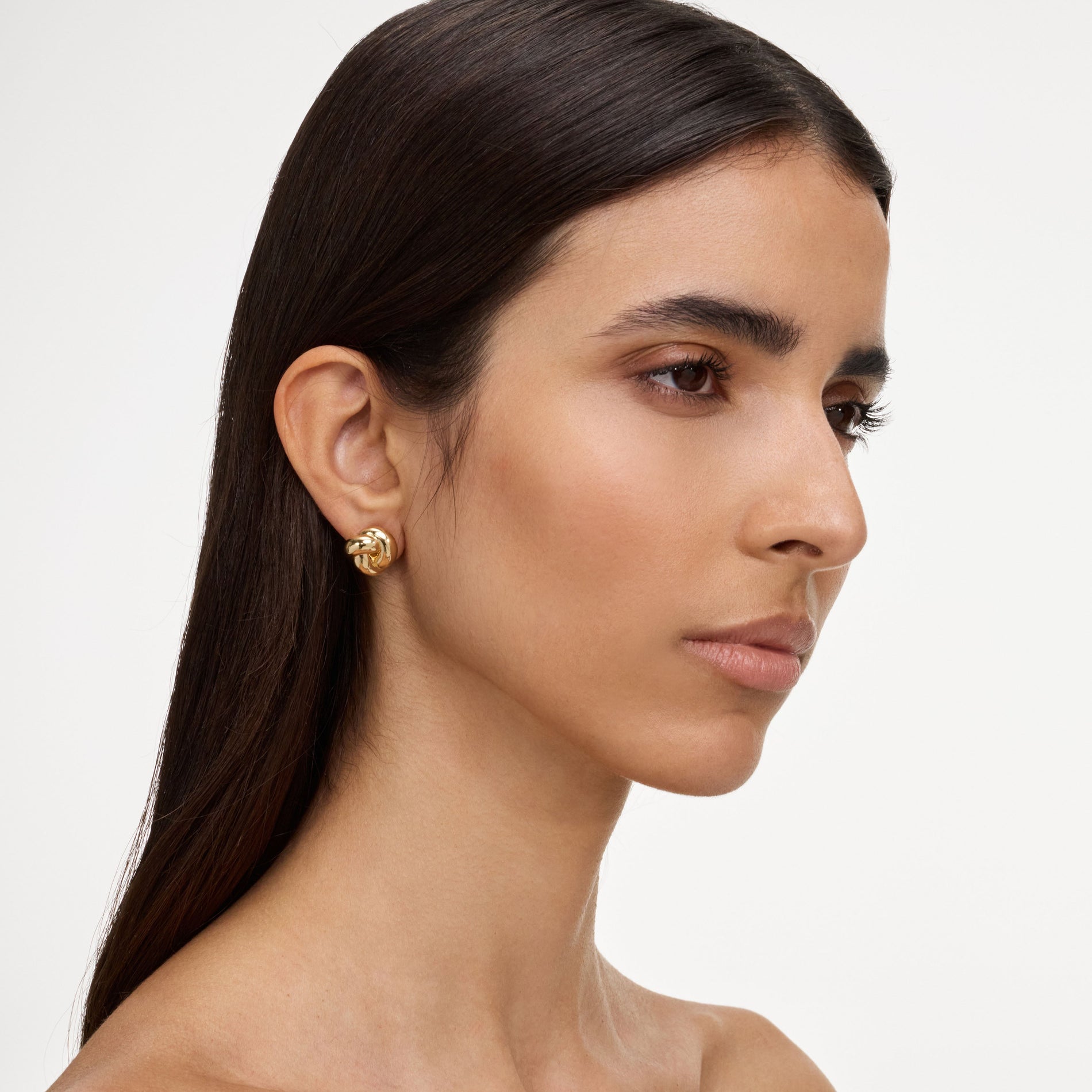 A close up of a woman wearing the Gold Small Knot Earrings