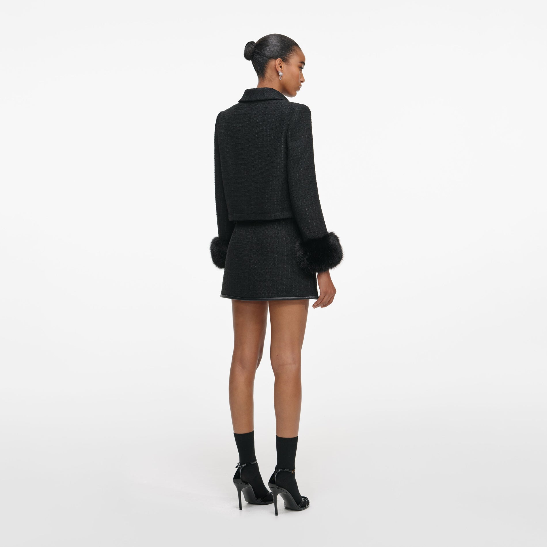 Back view of a woman wearing the Black Boucle Faux Fur Cuff Jacket