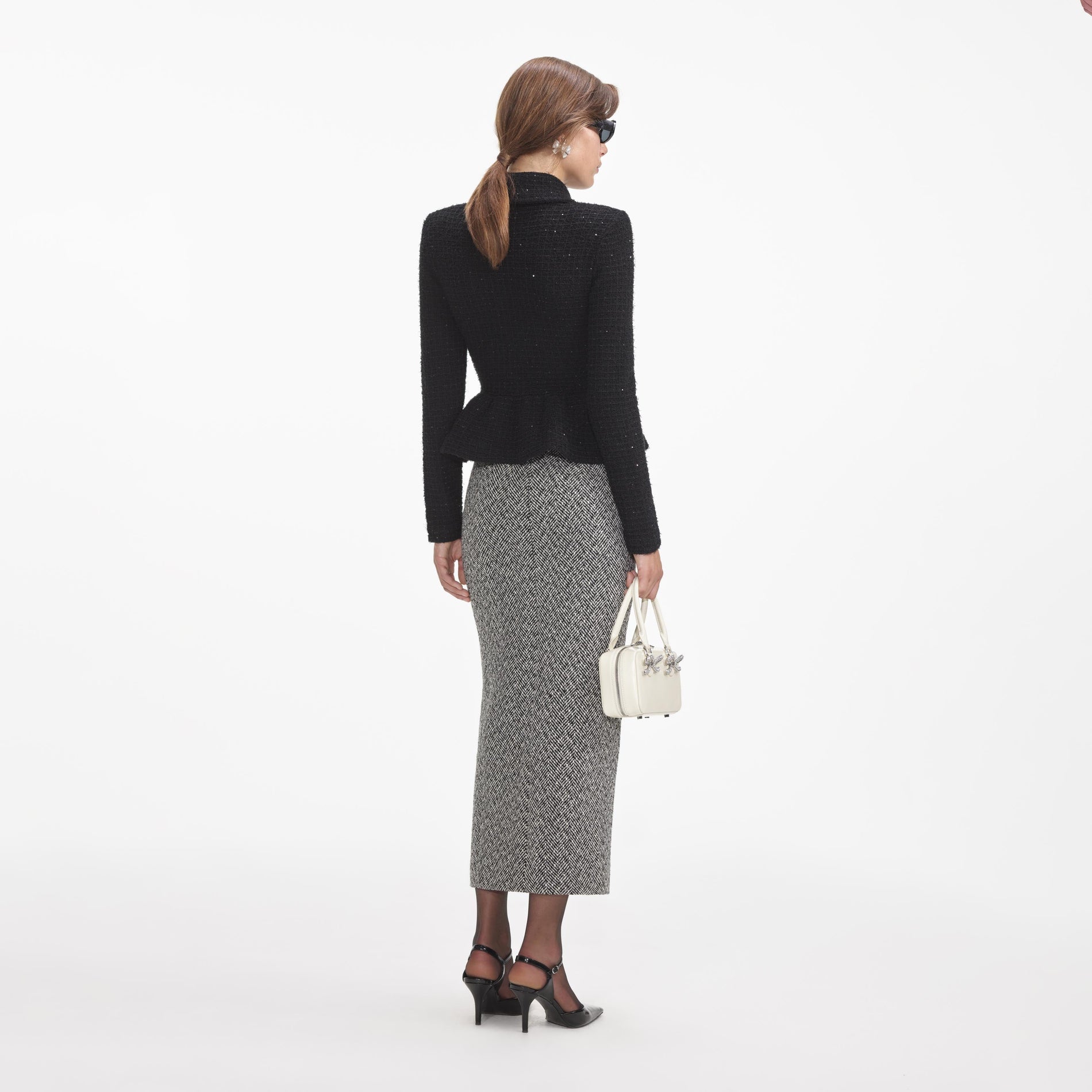 Back view of a woman wearing the Black Textured Knit Peplum Jacket