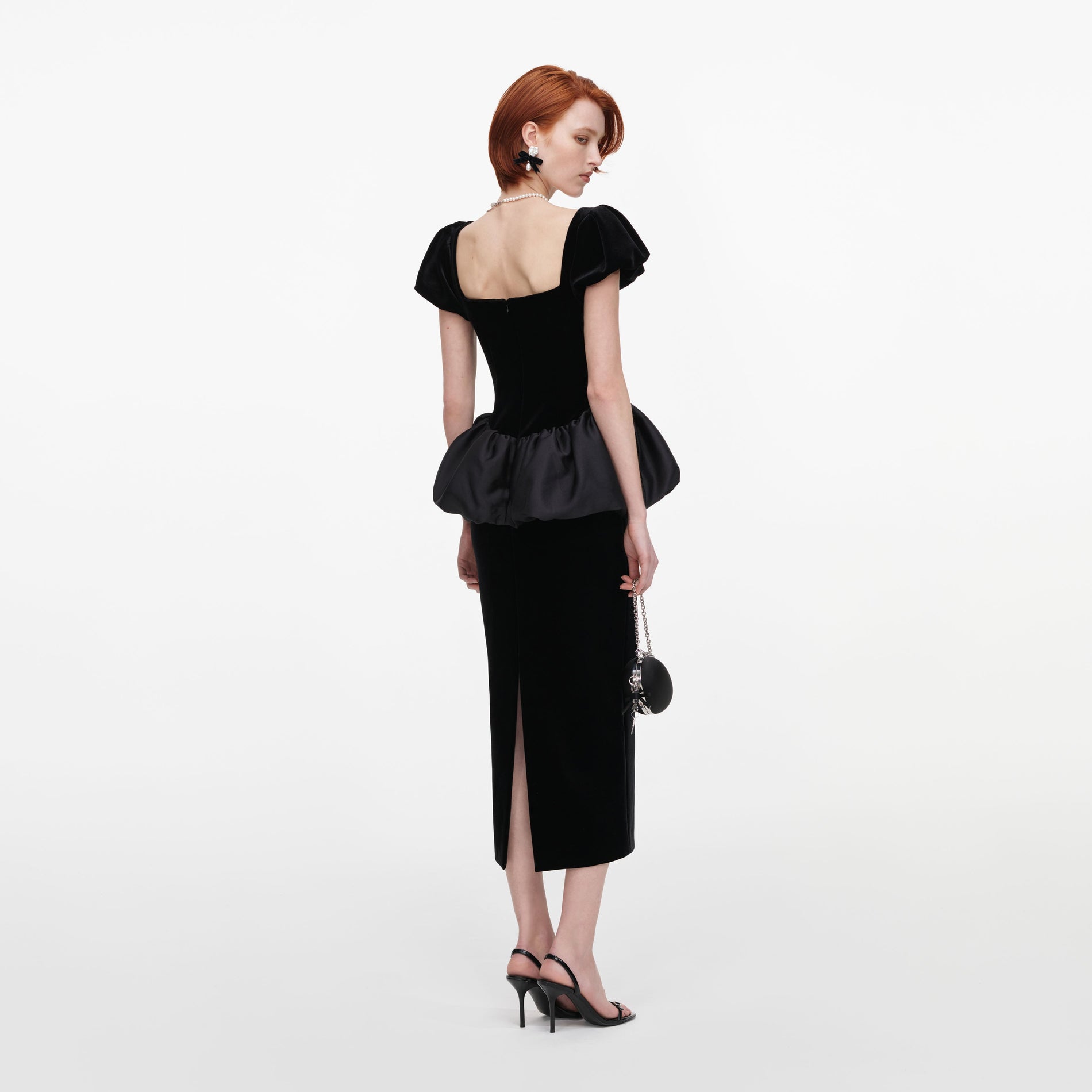 Back view of a woman wearing the Black Velvet Bubble Peplum Midi Dress