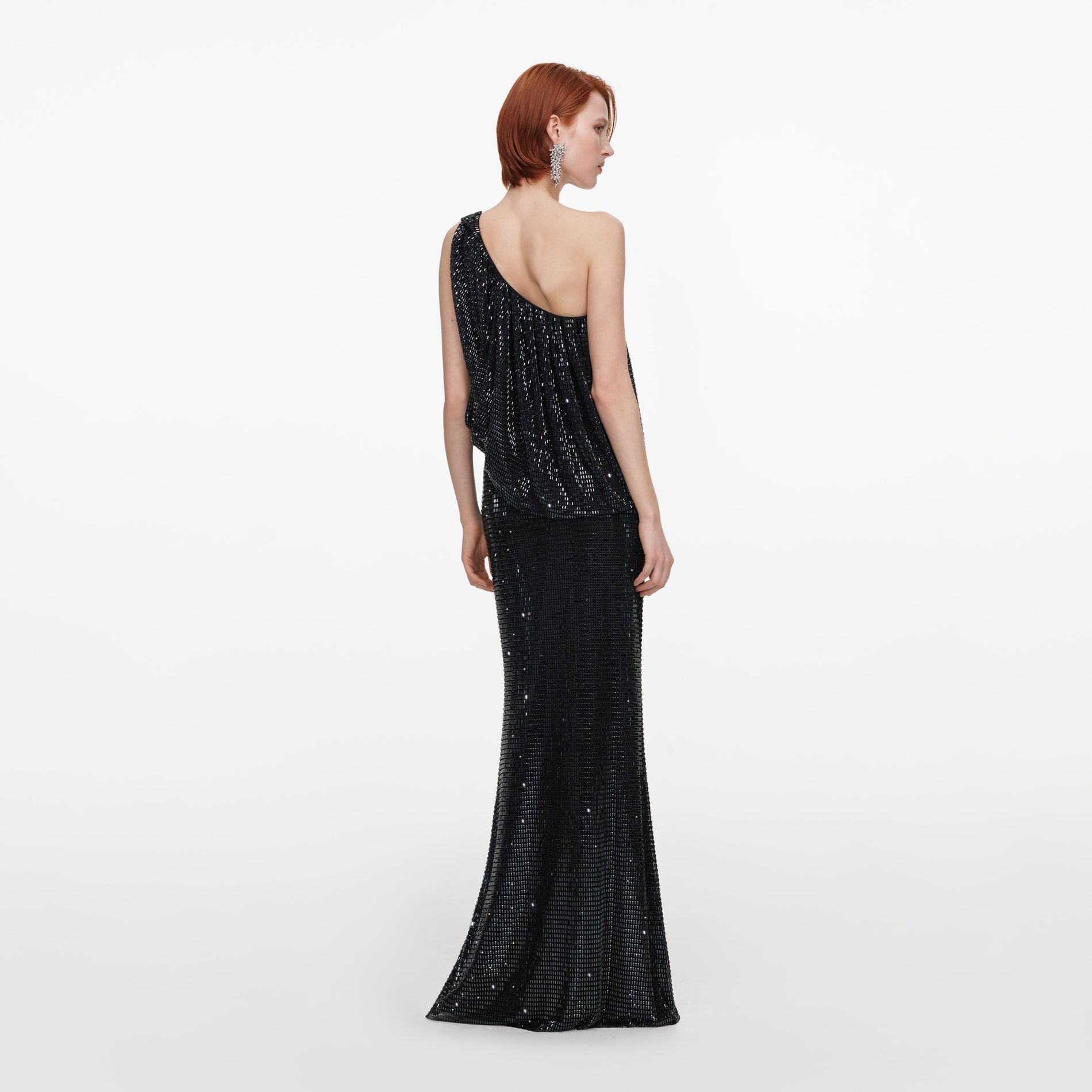 Back view of a woman wearing the Black Rhinestone One Shoulder Drape Maxi Dress